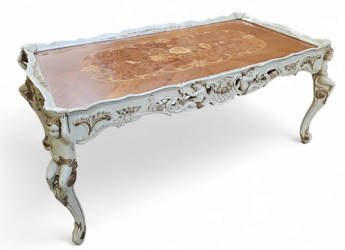 Rococo Style Marquetry Top Coffee Table: The table features intricate putti and floral carvings on the base and edges, and a floral inlaid marquetry table top. The item measures 17 1/2" tall, 38 7/8" wide, and 21" deep. There are some scuffs