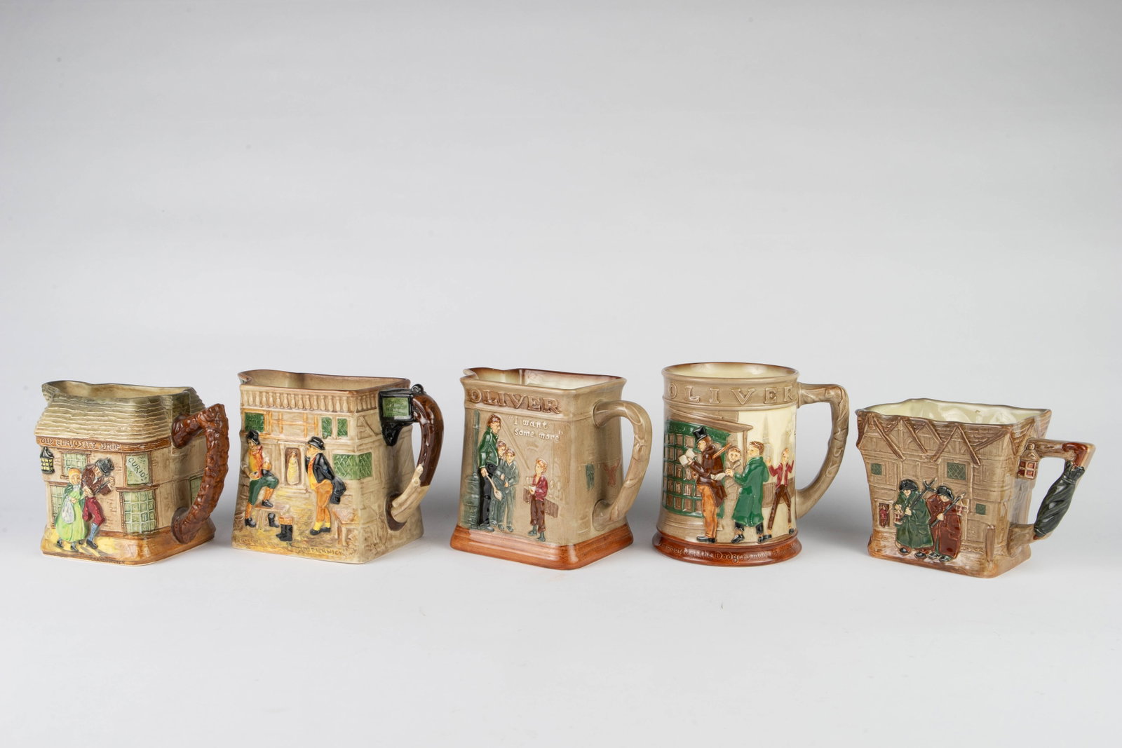 Lot of 5 Royal Doulton Charles Dickens Pitchers.: Actually, four of these are pitchers, while one is a large tankard mug. They feature relief scenes from classic Dickens works, including "Oliver Twist", "The Old Curiosity Shop", "Martin Chuzzlewit", 
