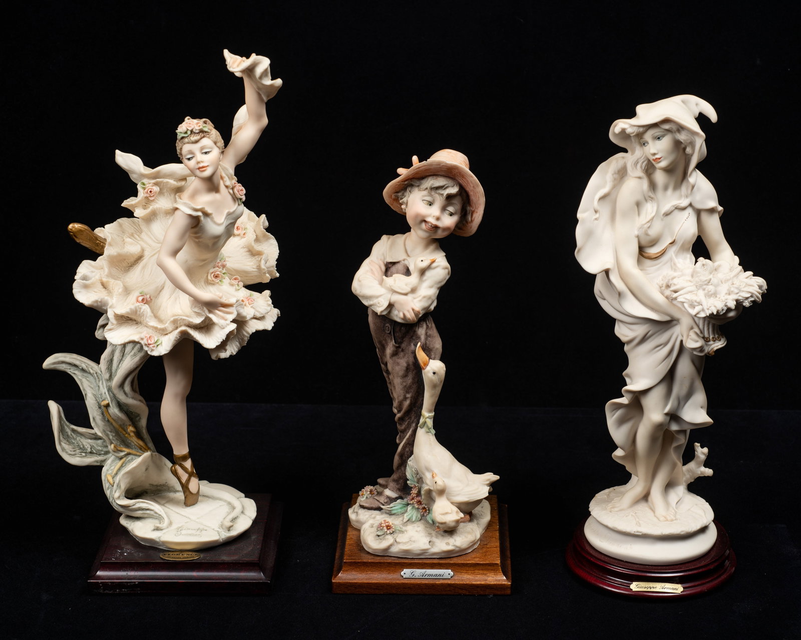 Lot of 3 Armani Figurines - Boy, Dancer, Harvest.: The lot includes a "Carla" ballerina figure, a farm boy with ducks (his hat has been repaired), and a Winter Lady w/ Cowl. Overall, the lot looks to be in good condition. The largest figurine measures