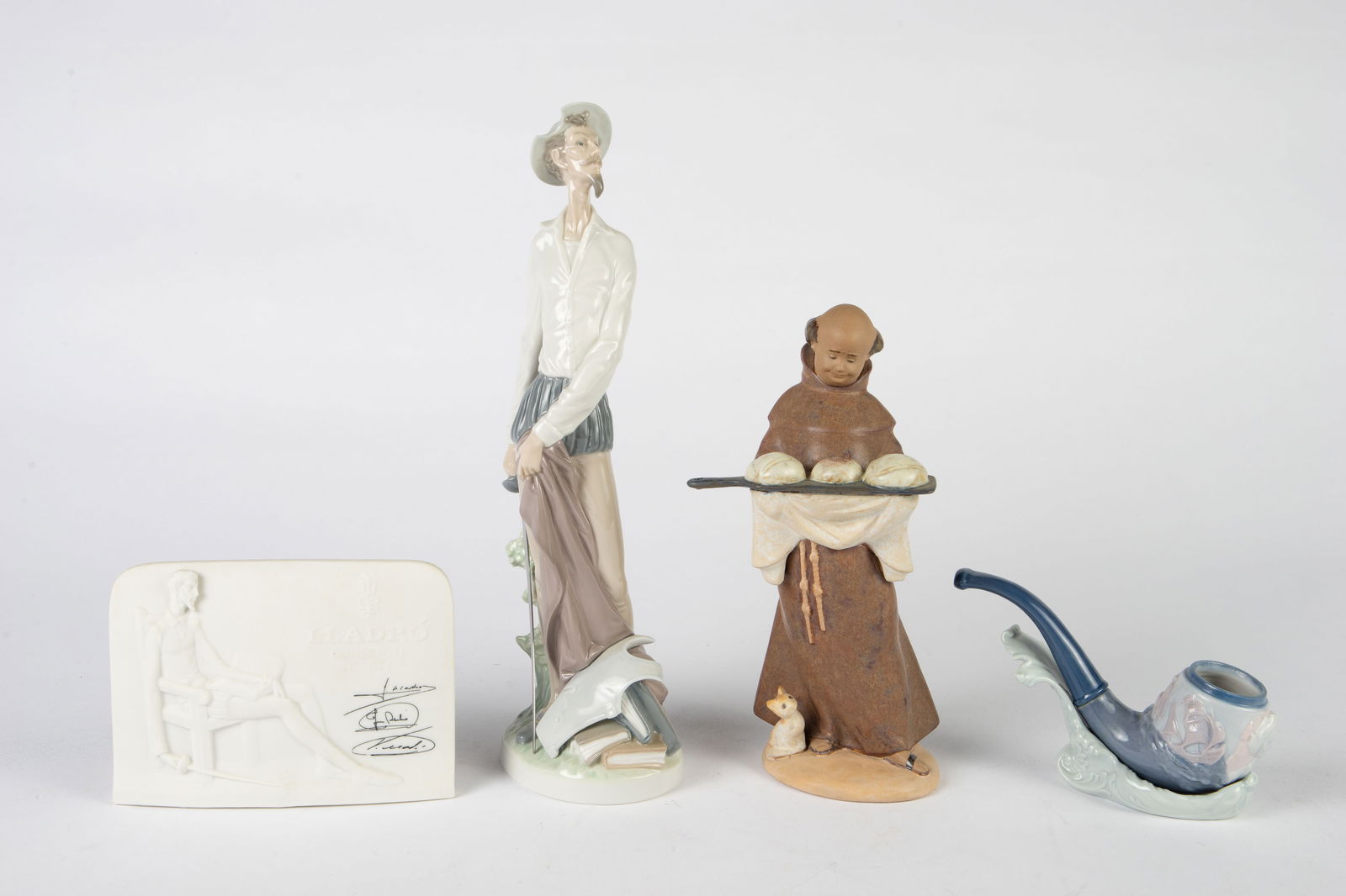 Lot: Lladro Don Quixote, Monk, Pipe, Plaque.: The lot includes a standing 12" Don Quixote figure, an "Our Daily Bread" monk, a Christopher Columbus pipe with stand, and a Collector's Society plaque. The lot looks to be in very nice condition. In-