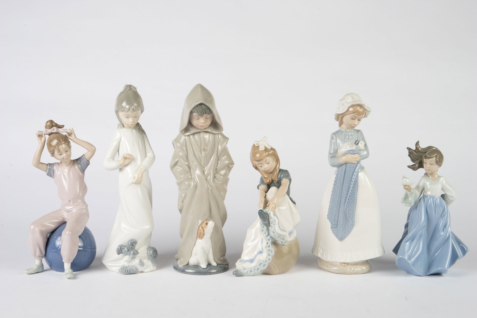 Lot of 5 Nao by Lladro Child Figurines.: The lot includes a girl on a ball, a girl holding a bird, a girl holding a puppy, a boy with a dog at his feet, a girl taking her shoes off, and a girl with a dog tugging at her nightgown. The lot loo
