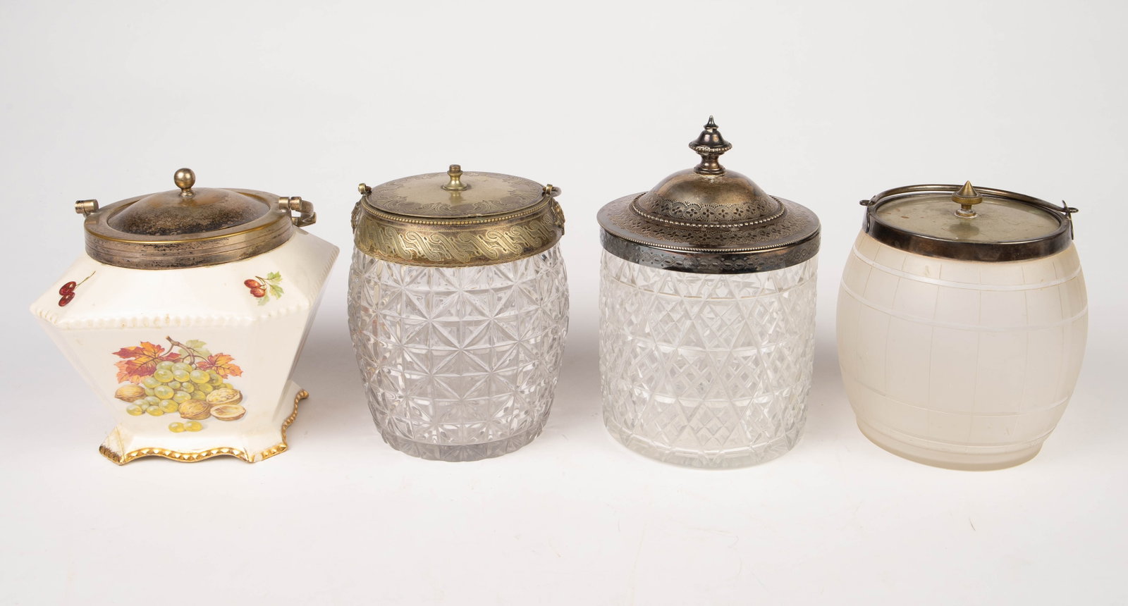 Lot of 4 Antique Biscuit Jars- Crystal, etc.: This lot includes two barrel shaped biscuit jars with handles; one is crystal with a silverplate rim mount and lid. The rim mount has two soldier head decorations just under the handles. There is also
