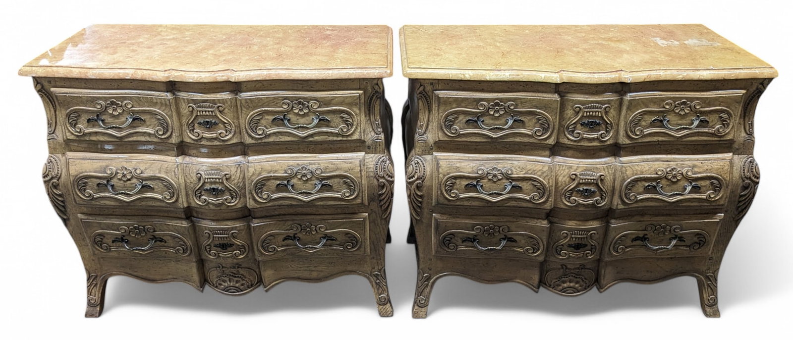 Pair of French Style Bombe or Bombay Chests.: The chests have laminate tops, and feature three drawers each. The drawers have carvings of lyres and flowers, brass pulls, and decorative escutcheons. One of the chests has heavy laminate damage. Oth