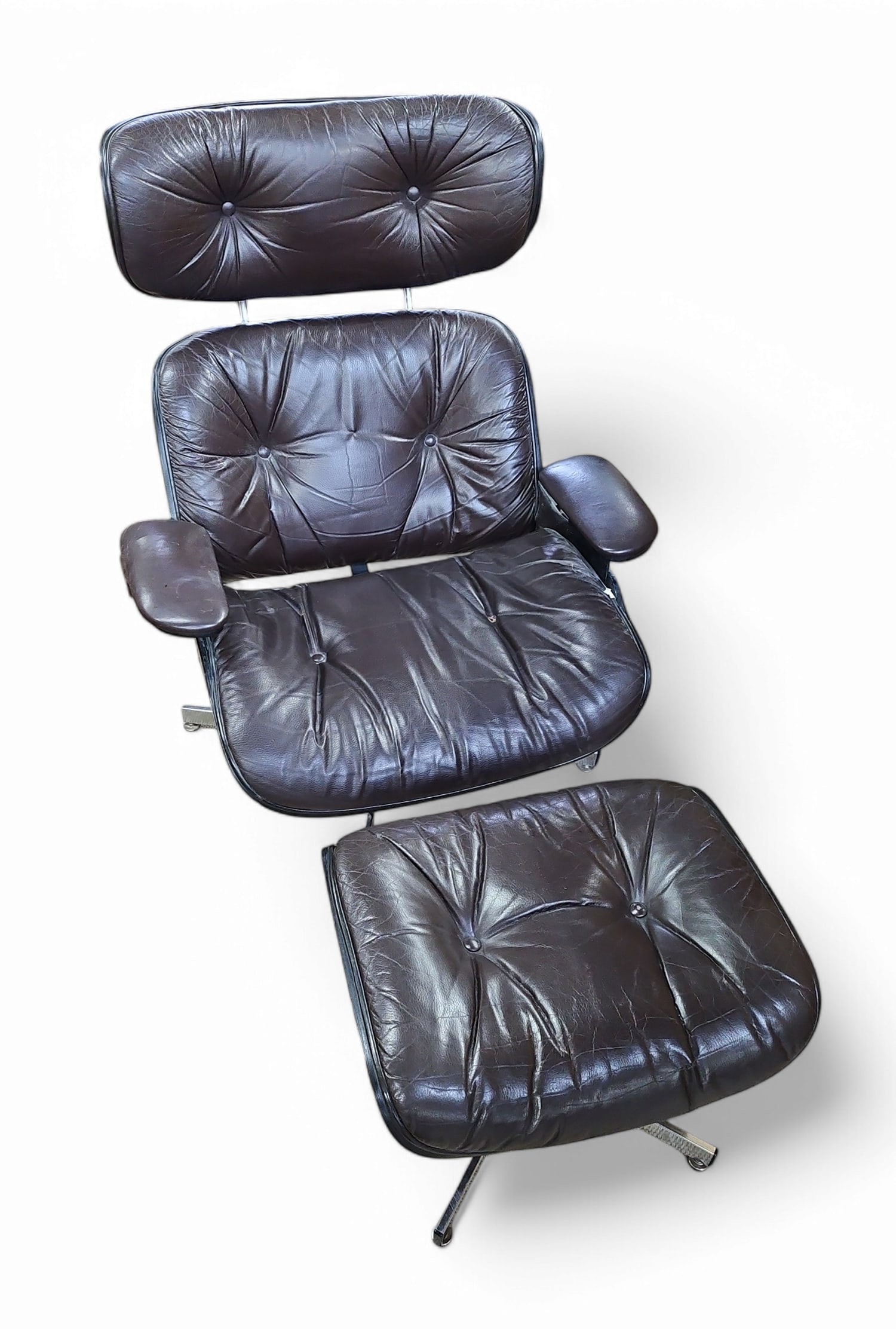 Eames Style Lounge Chair & Ottoman.: This vintage Eames style dark brown leather recliner and ottoman have a dark walnut wood grain, button tufted design, chrome legs, and a back rest support. The recliner measures 39 1/2" tall, 31" wide
