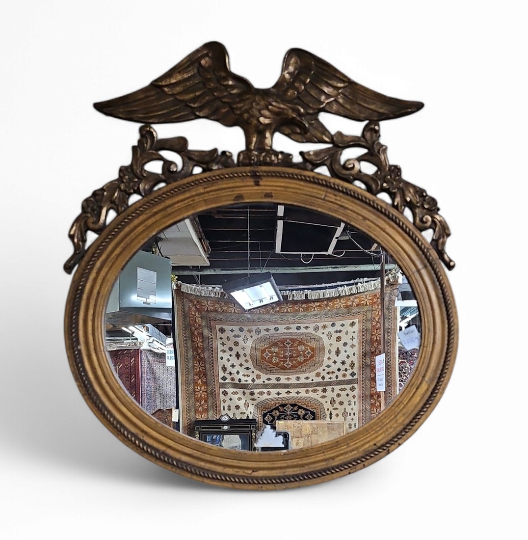 Federal Style Wall Mirror with Eagle.: This gilt oval wall mirror features decorations of an eagle and flowers. It is in good condition for its age, with some scratches and stains. It measures 22" tall and 19" wide. Third-party freight shi