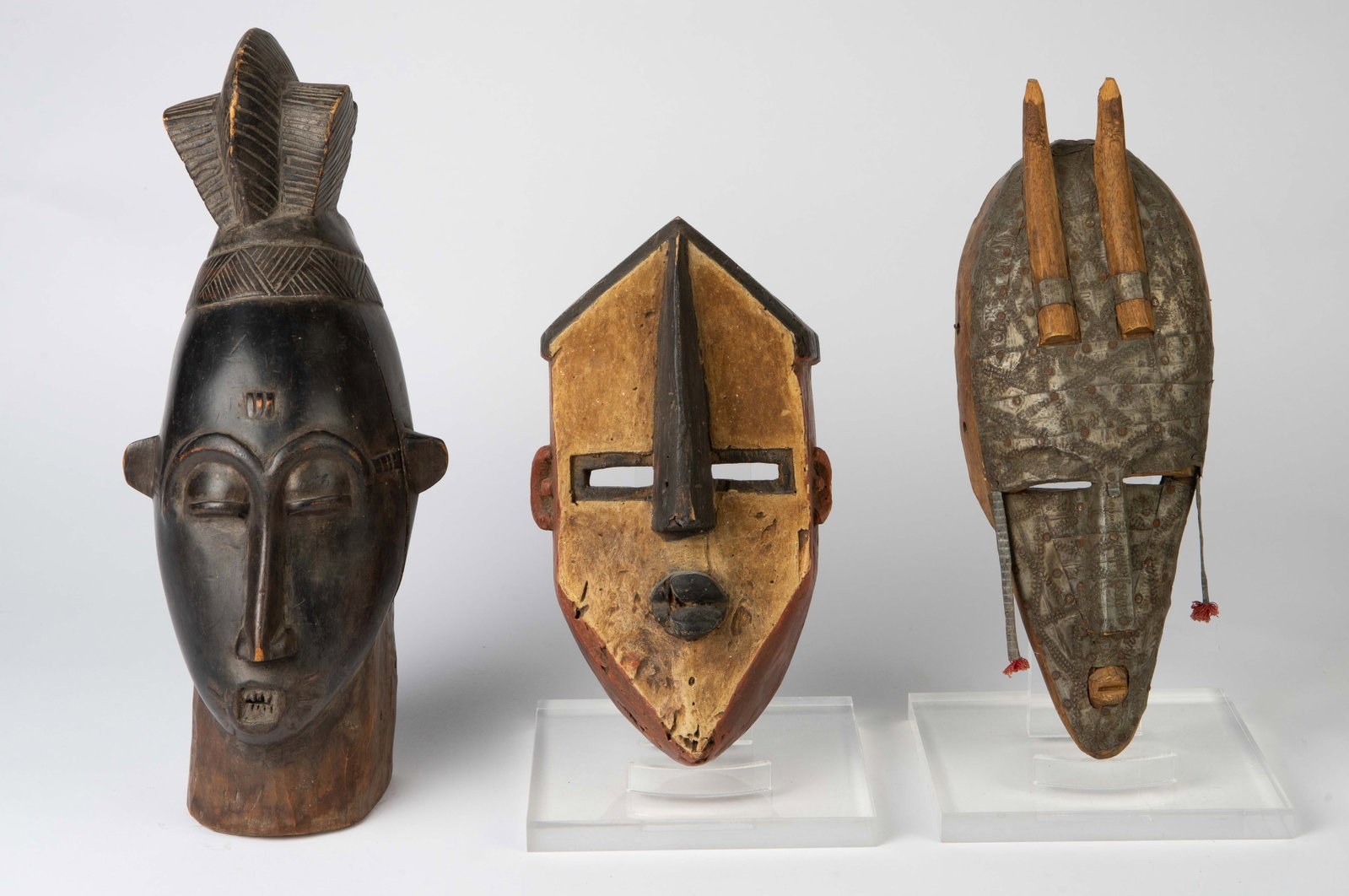 3 African Tribal Masks - Congo, Baule, Marka.: The lot consists of 3 carved wood African masks. First, there is a multicolored geometric piece attributed to ancient Congo. Next, there is a horned Marka mask with metal overlay. The last mask is a B