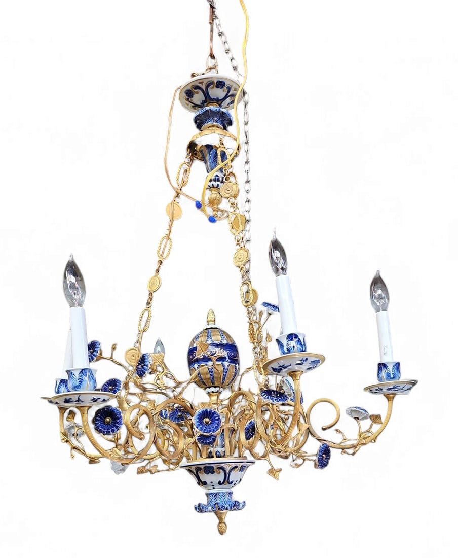 Ornate Delft Blue Chandelier w/ Gilded Leaves.: This 6-arm electrified gilded metal and porcelain chandelier looks to be in overall good condition. The gilded arms are covered in gold vines with pointed leaves and blue button-like flowers. There ar