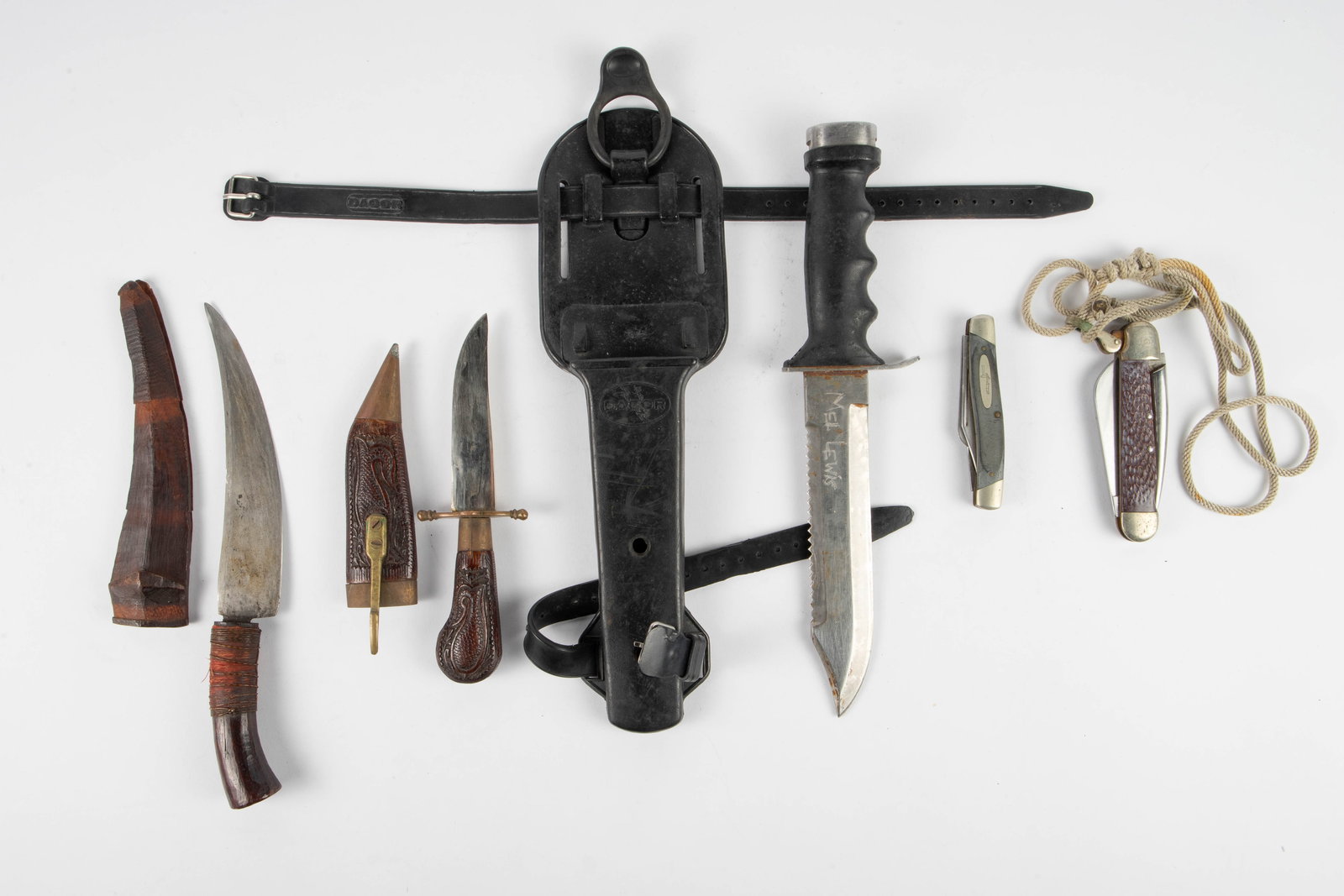 Lot of 5 Knives, including Buck & Dacor.: This lot includes a Dacor hunting or military knife with black sheath, an unmarked vintage hunting knife with carved scabbard and handle, a curved knife of likely foreign origin, a Buck folding utilit