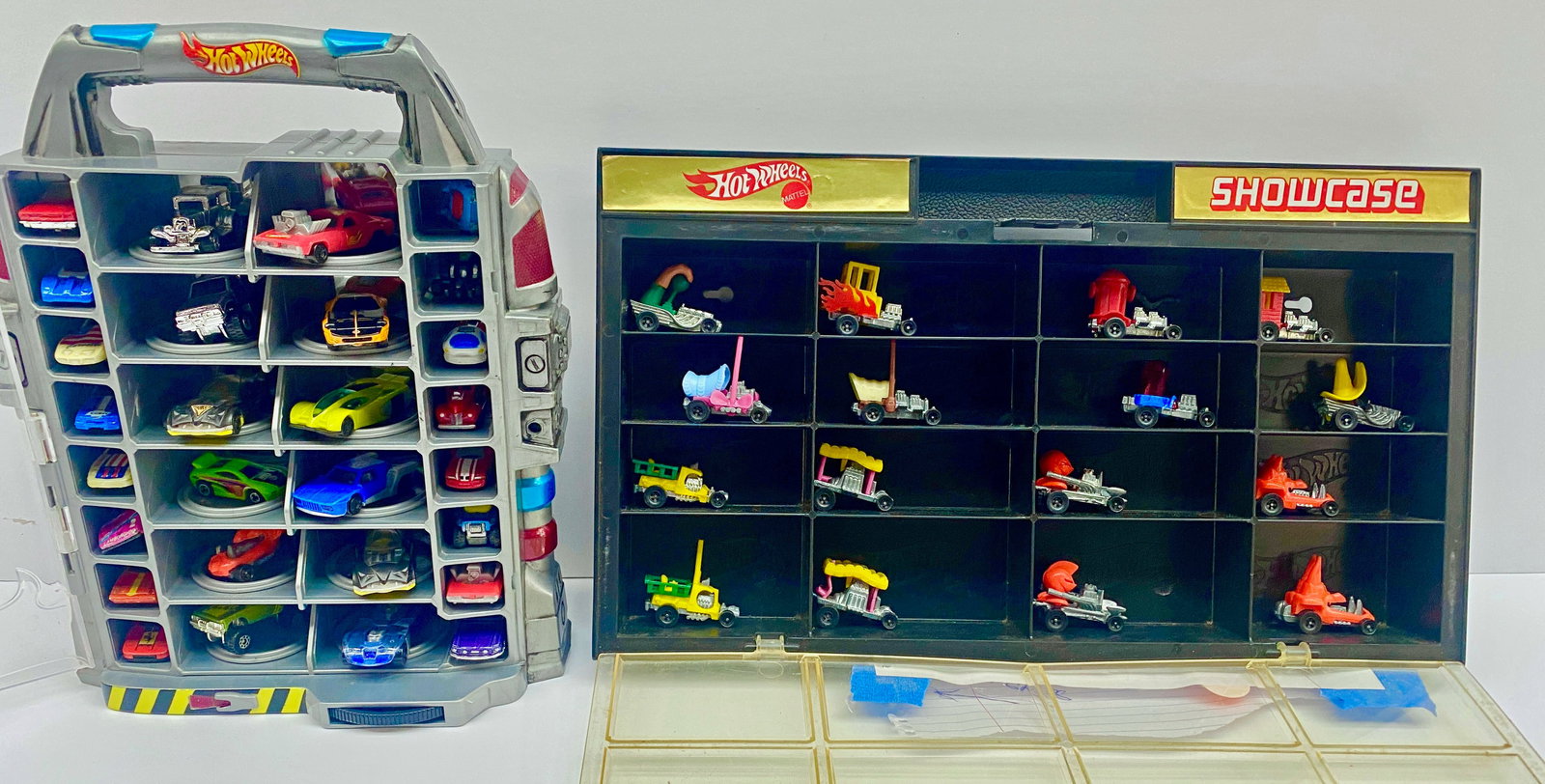 44 Hot Wheel Zowees Cars from 1972 and On.: The lot contains 2 Hot Wheels showcases with every slot taken by a car. The oldest date observed is 1972. The largest case measures 14" x 8" x 1 3/4". Some of the items are worn, and others are in ove