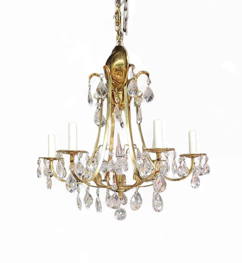 6-Arm Brass & Glass Prism Chandelier.: The lighting fixture features teardrop glass prisms and a brass body. It measures 20 1/2" x 20 1/2" x 20 1/2". One of the prisms towards the top is chipped. There are some chips on the faux candle pos