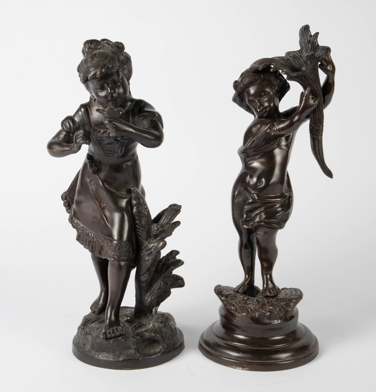 Lot of 2 Bronze Children, After Rousseau & Moreau.: The sculpture signed, "Moreau" depicts a barefoot girl in a dress, smelling a flower. The sculpture signed, "Rousseau" depicts a nude boy or Putti holding a cornucopia (not attached). There are some s