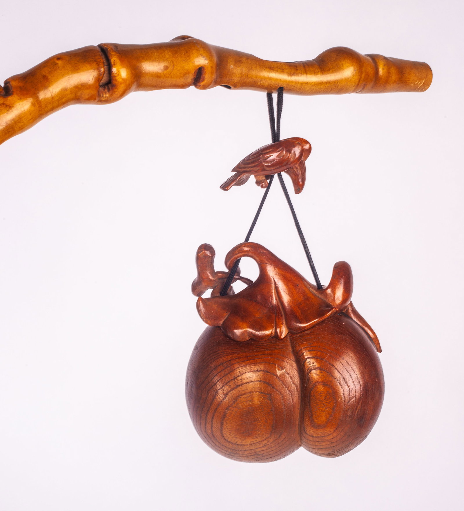 Chinese Wood Carved Longevity Ornament.: The piece is a box in the shape of a peach, which represents longevity. It is hanging from a bamboo shaped carved wood branch by a brown cord. the peach and bird portion measures 4 3/4" long by 3 3/4"