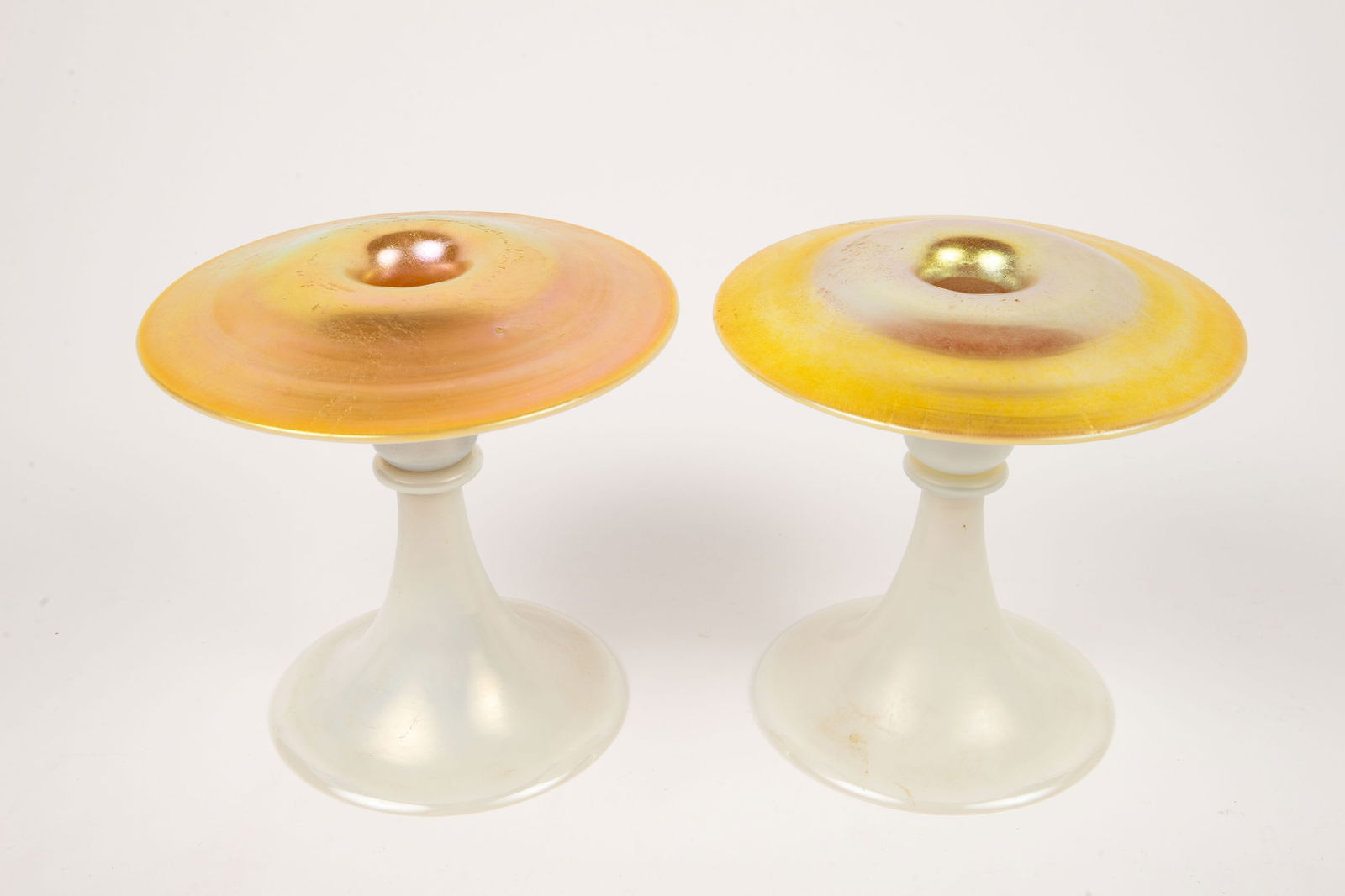 Pair of Steuben Aurene Calcite Candlesticks.: These glass candleholders are unsigned. They are white and gold. One of them has more scratches on the gold surface than the other one does; overall, the pair look to be in good condition. Each one me