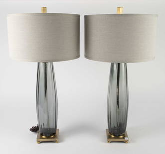 Pair of Uttermost Glass & Brass Table Lamps.: The pair of large contemporary lamps feature ribbed smoky glass posts, brass bases, and light gray linen drum shades. They are marked Uttermost Est. 1975 on the knobs. Each piece measures 32" x 17" x