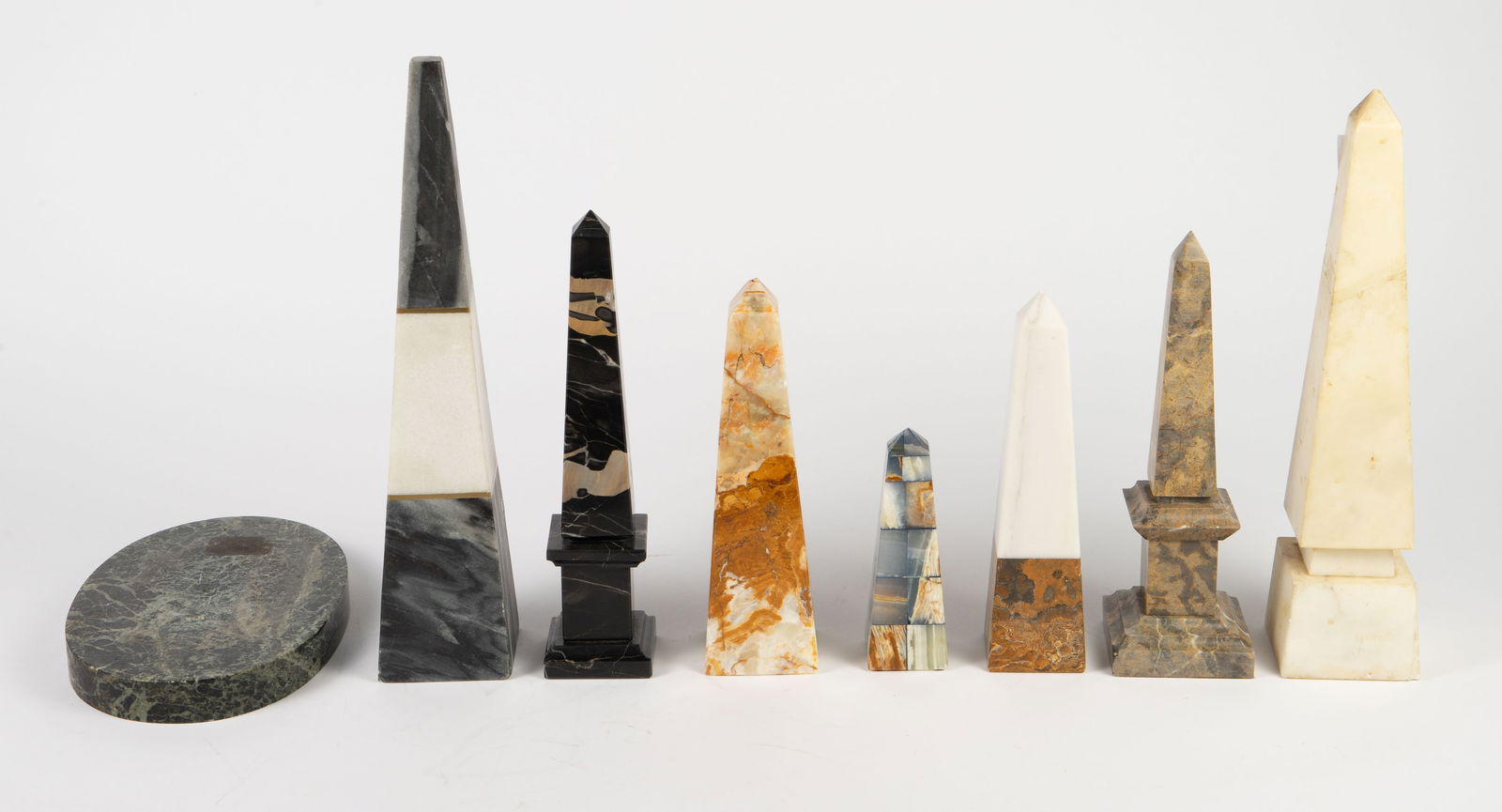 Lot: 8 Pcs.- Mostly Stone Obelisks.: Seven of the pieces are obelisks, one is an oval base. There are some scratches and chips present. The obelisks include onyx, marble, and other stone materials. The largest one measures 3 1/2" x 3 3/8