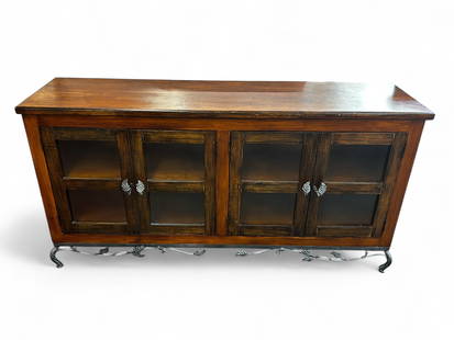 Wood Sideboard or Buffet w/ Wrought Iron Leaf Base: This stained and varnished piece has four doors with panel style glass inserts, two interior shelves, floral wrought iron door pulls, and wrought iron legs with leaf decorations. There are some scratc