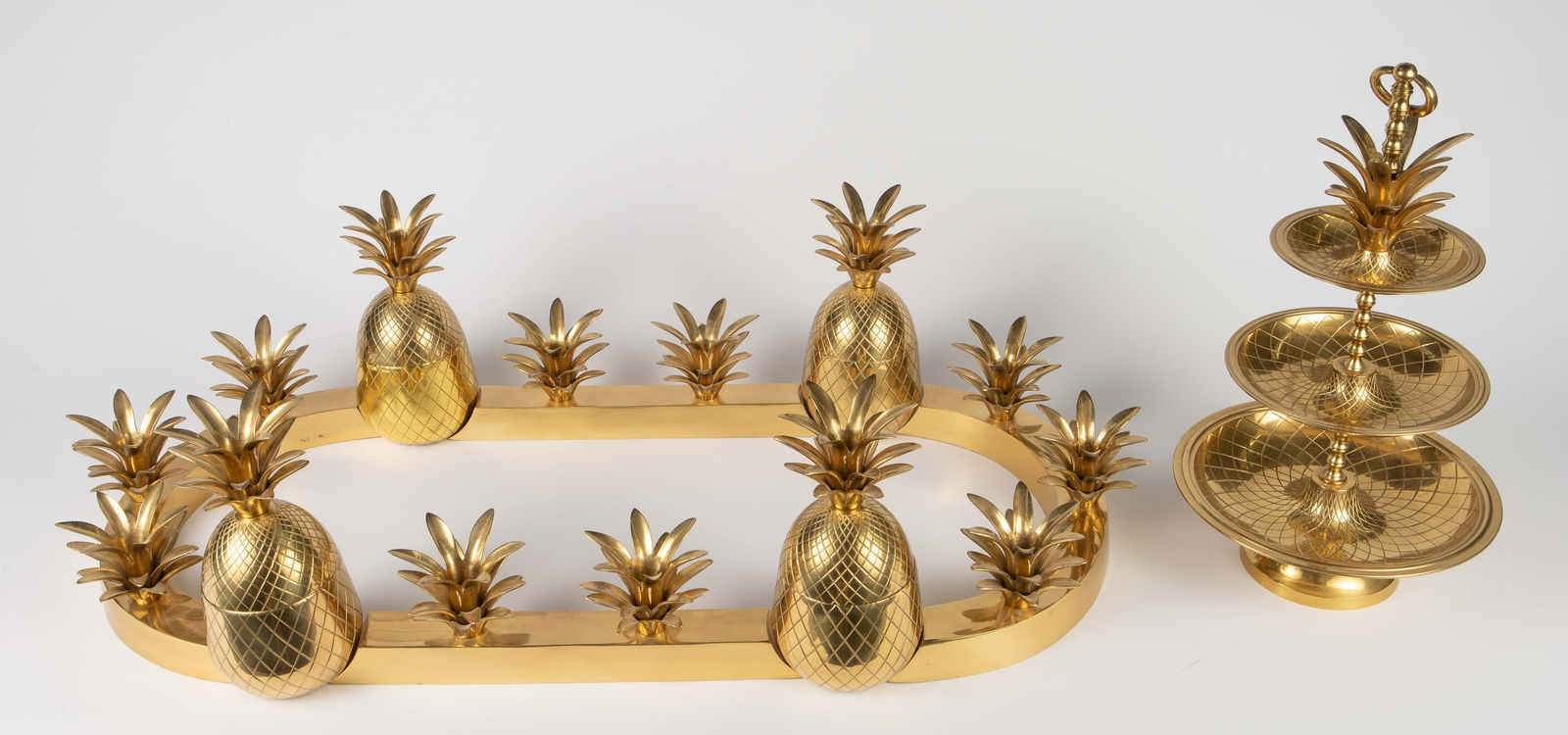 Ethan Allen Brass Pineapple Table Set.: The pineapple jars are labeled as Ethan Allen. The lot consists of four matching pineapple jars, a set of 10 pineapple leaf candle holders, and a pineapple-themed tiered tray centerpiece. Overall, the