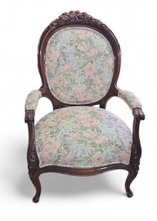 Antique Carved Upholstered Armchair.: The arm chair features decorative flower and fruit carvings on the top of the back, and carvings on the arms and legs. It has a green, pink and white floral upholstery. It measures 40 1/2" x 27 1/4" x