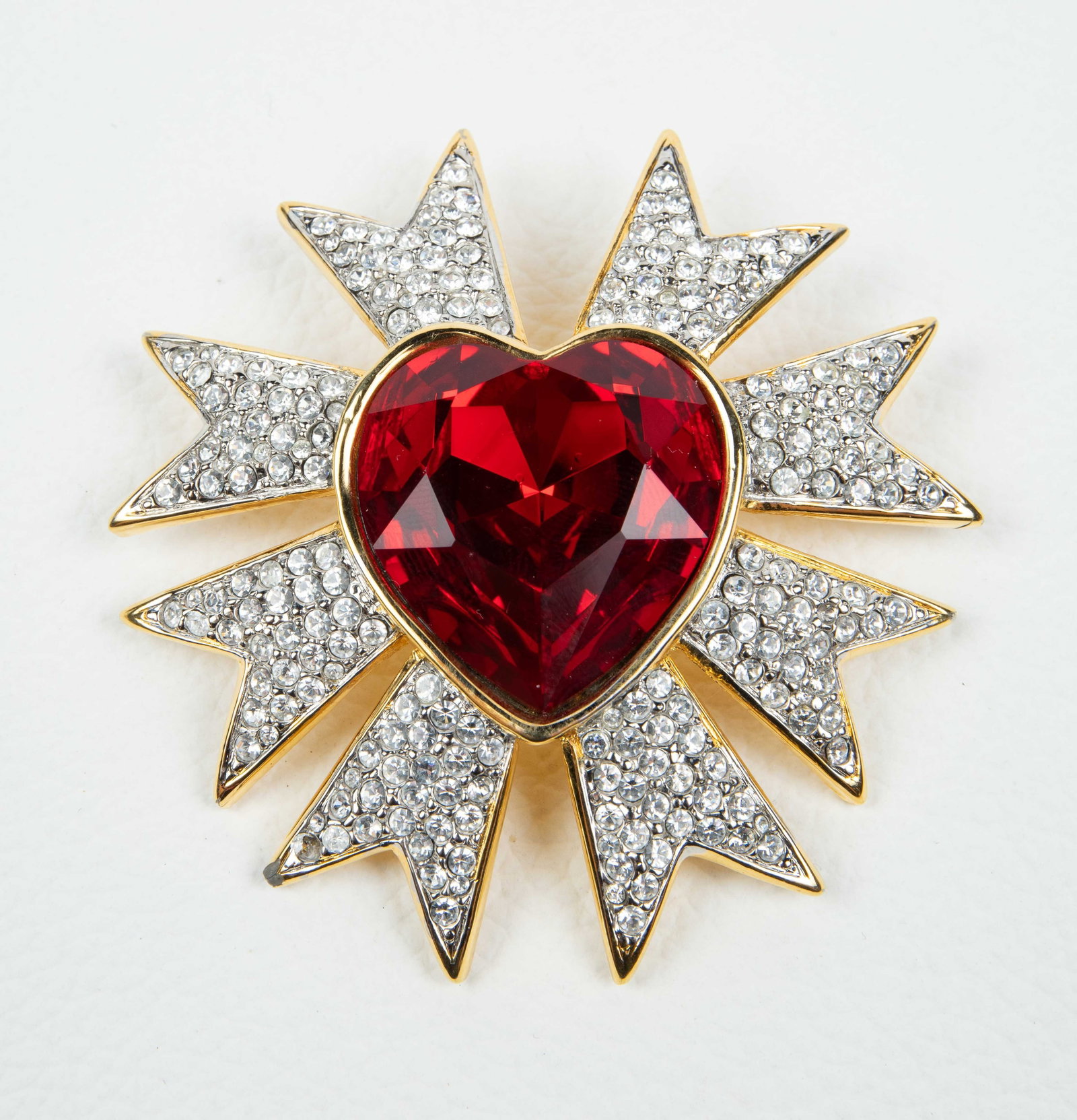 Vintage Valentino Heart Burst Rhinestone Brooch.: The designer brooch features a large faceted red rhinestone heart surrounded by sunburst style extruding lines with clear rhinestone clusters. The gold toned metal is branded V on the back. It measure
