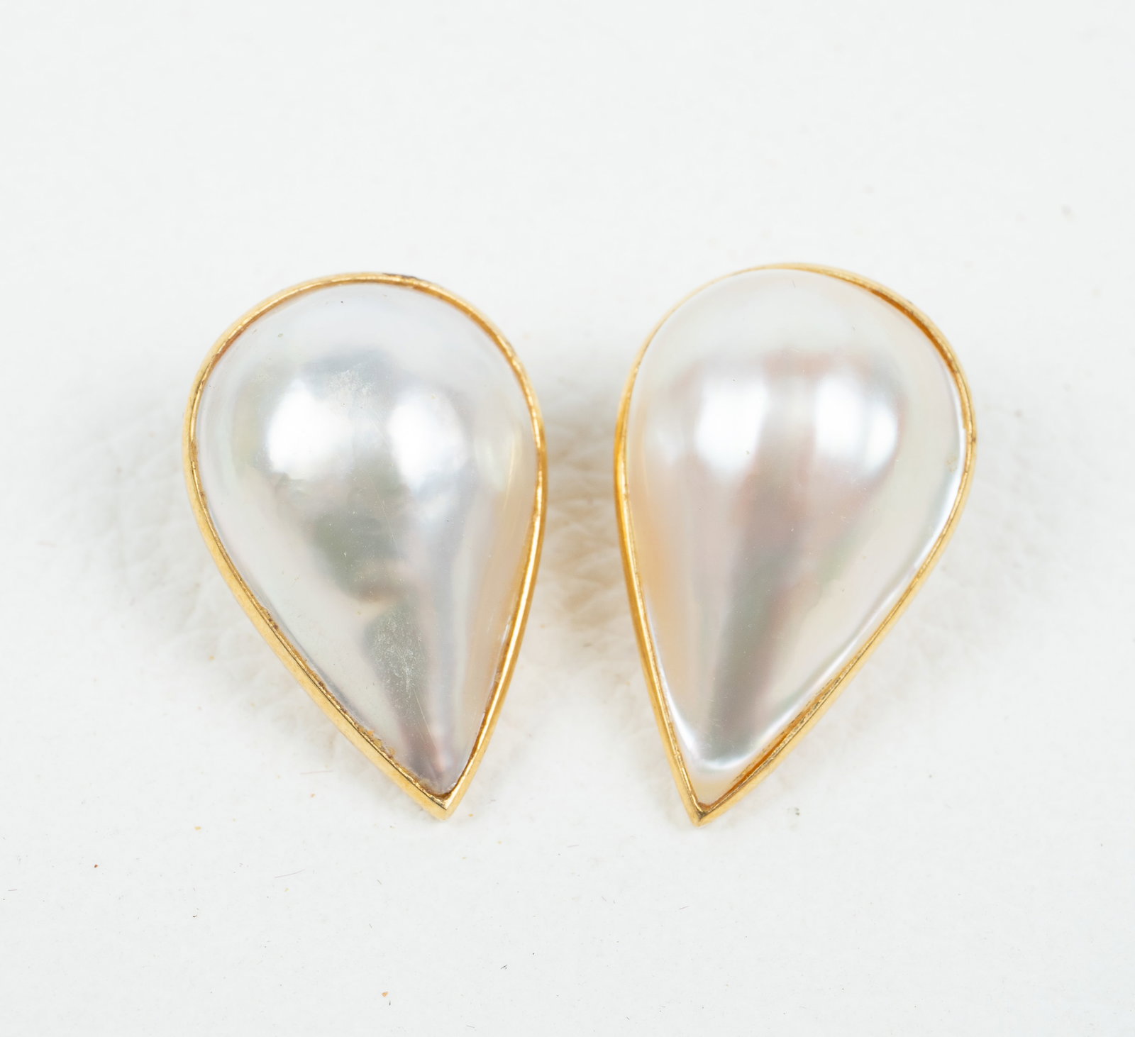 Pair of 18K Gold Teardrop Mabe Pearl Earrings.: The pair of earrings are marked 18K 750, along with a maker's mark of a JC inside a hexagon. They feature teardrop-shaped pearls with flat backs. Each measures 1" x 5/8". They have some light scratche