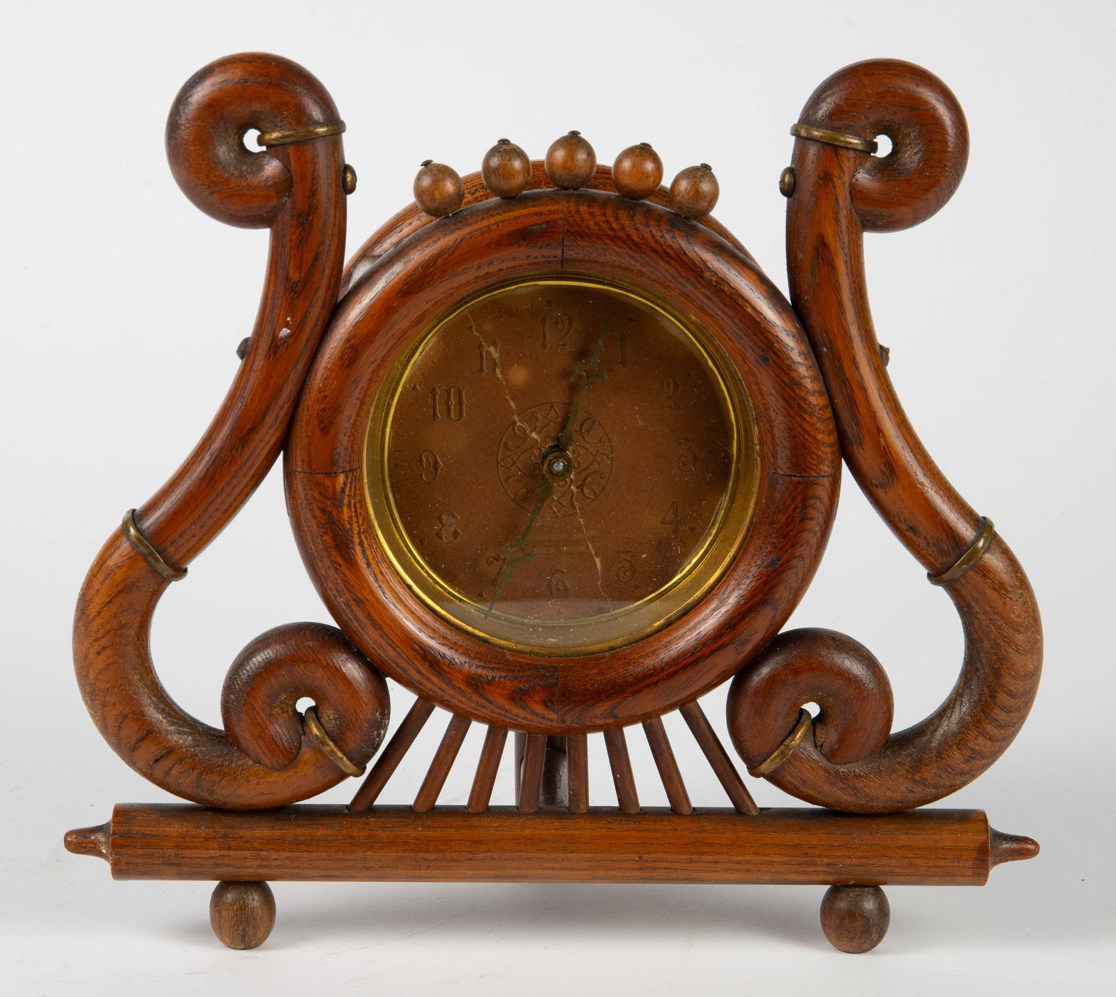 Ferguson Bros. Stick & Ball Oak Desk Clock.: The clock features brass hardware, carved oak wood, and stick and ball designs. The face, which is cracked or ripped, is marked Ferguson Bros. New York. It measures 9" x 9 7/8" x 3 1/2". It is not cur