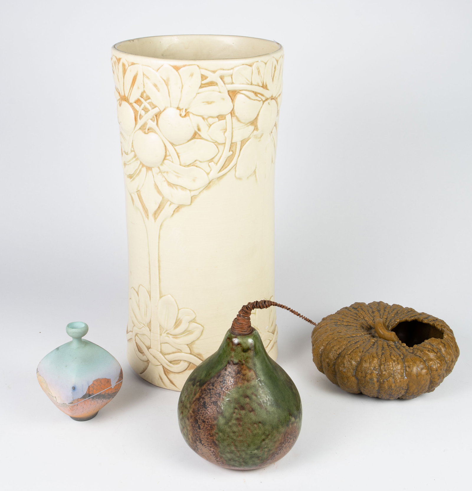 Lot of 4 Assorted Pottery Pieces.: The lot includes an art nouveau umbrella stand with tree and fruit designs, a pear-shaped decoration, a pumpkin like piece, and a small blue & brown vase (some chips on the rim). The small vase is the