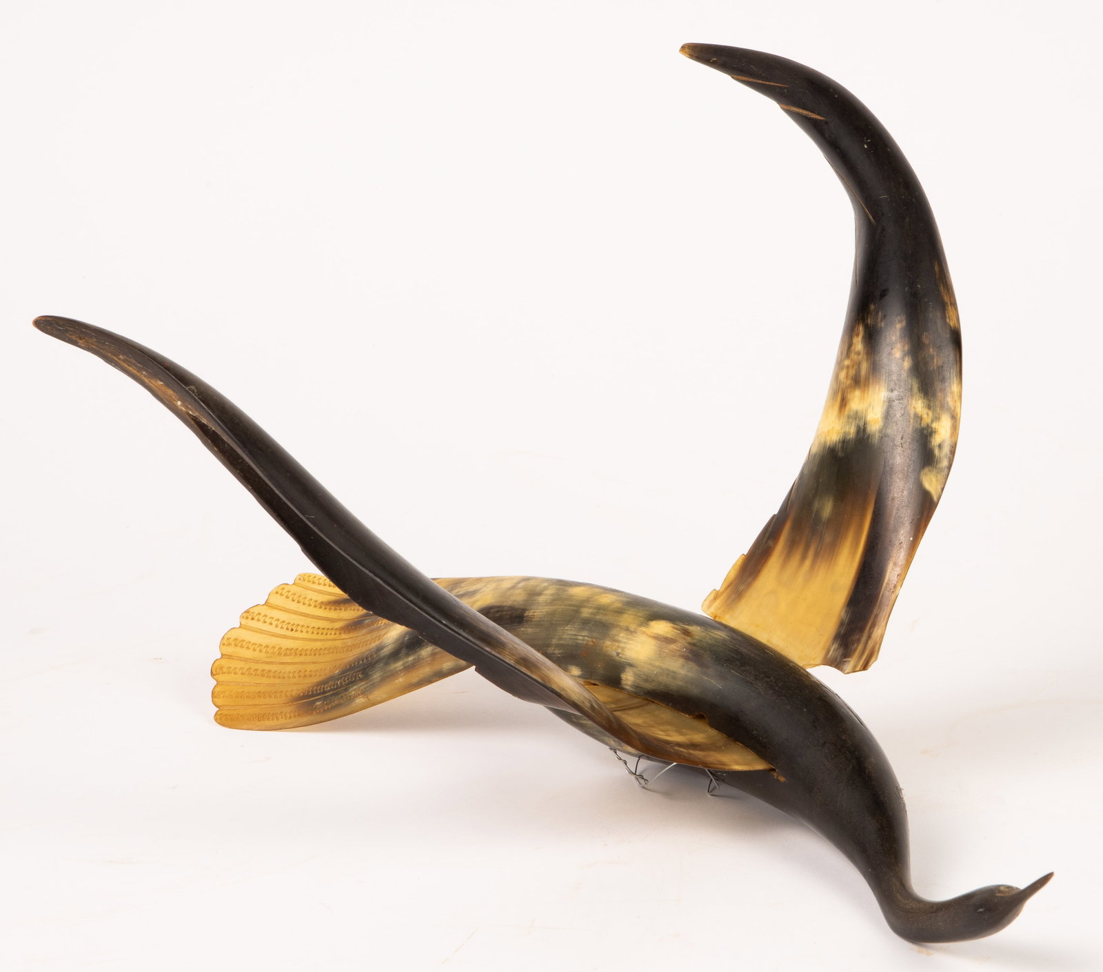 Carved Horn Suspended Bird Sculpture.: The sculpture depicts a bird with a long neck and long wings. It is meant to be suspended in the air. It measures 16 1/2" x 12" x 9 1/4". One of the wings is chipped at its base, which leads to the wi