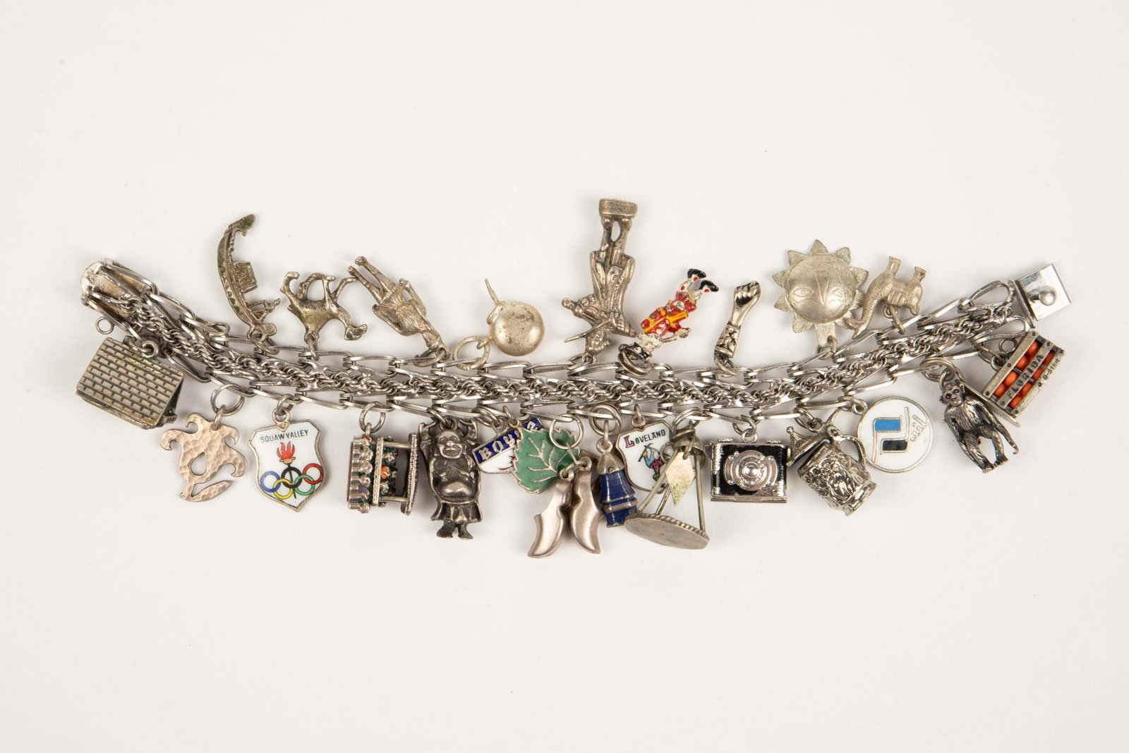 Vintage Silver Charm Bracelet w/ 25 Charms.: The silver charm bracelet is marked Sterling on the clasp, along with a maker's mark. At least 11 of the charms are also silver. Some of the charms are marked, while others aren't. The marks observed 