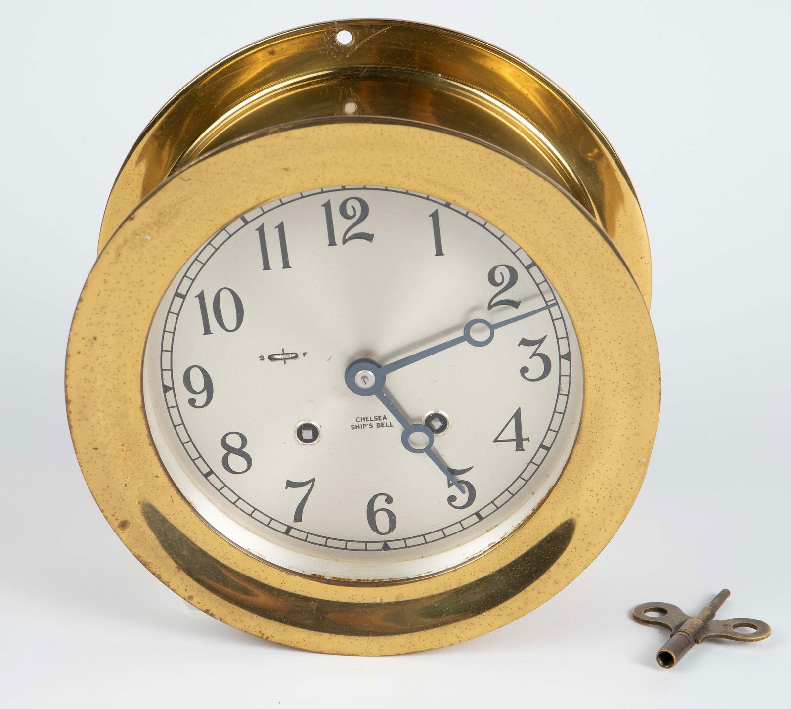 7 1/4" Diameter Chelsea Ship's Bell Brass Clock.: The keywind clock has a brass 7 1/4" x 3 1/2" case with three perforations on the back lip for mounting. It comes with a key. The clock ticks quietly, and keeps good time, but it does not chime. There