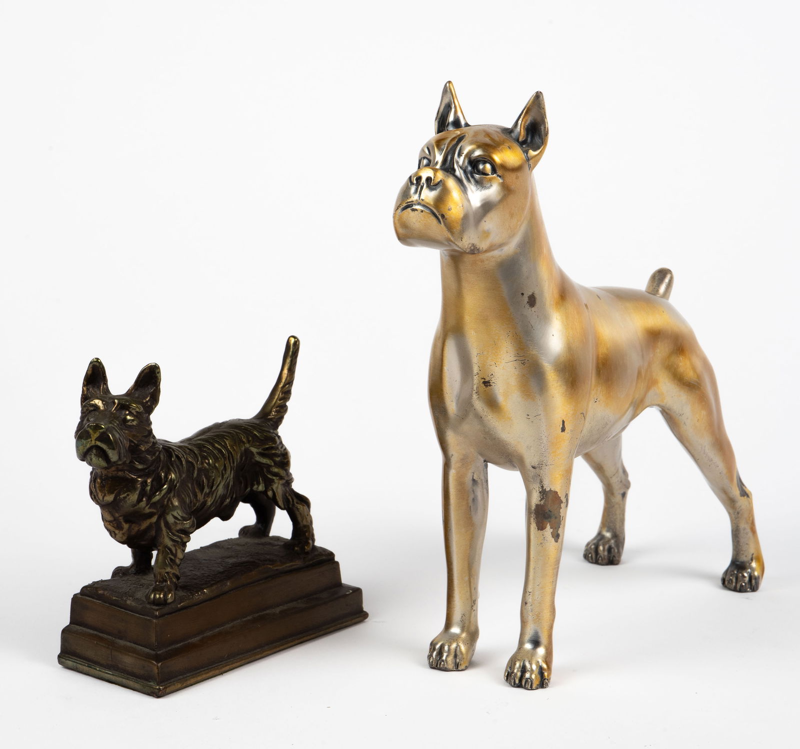 2 Metal Dog Sculptures - Boxer, Scottish Terrier.: The lot includes a heavy Boxer sculpture or doorstop with a brushed golden finish. It measures 10" x 9" x 3 5/8". Next, there is a smaller bronze finish Scottish Terrier bookend on a tiered base. It m