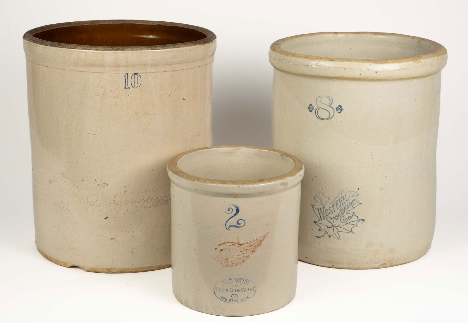 Lot of 3 Vintage Crocks- 10, 8, & 2 Gallon.: The 2 gallon crock is by Red Wing. The 8 gallon crock is by Western Stoneware Co. The 10 gallon crock is by an unknown maker. This last crock has some damage - chips along the bottom, and a crack that