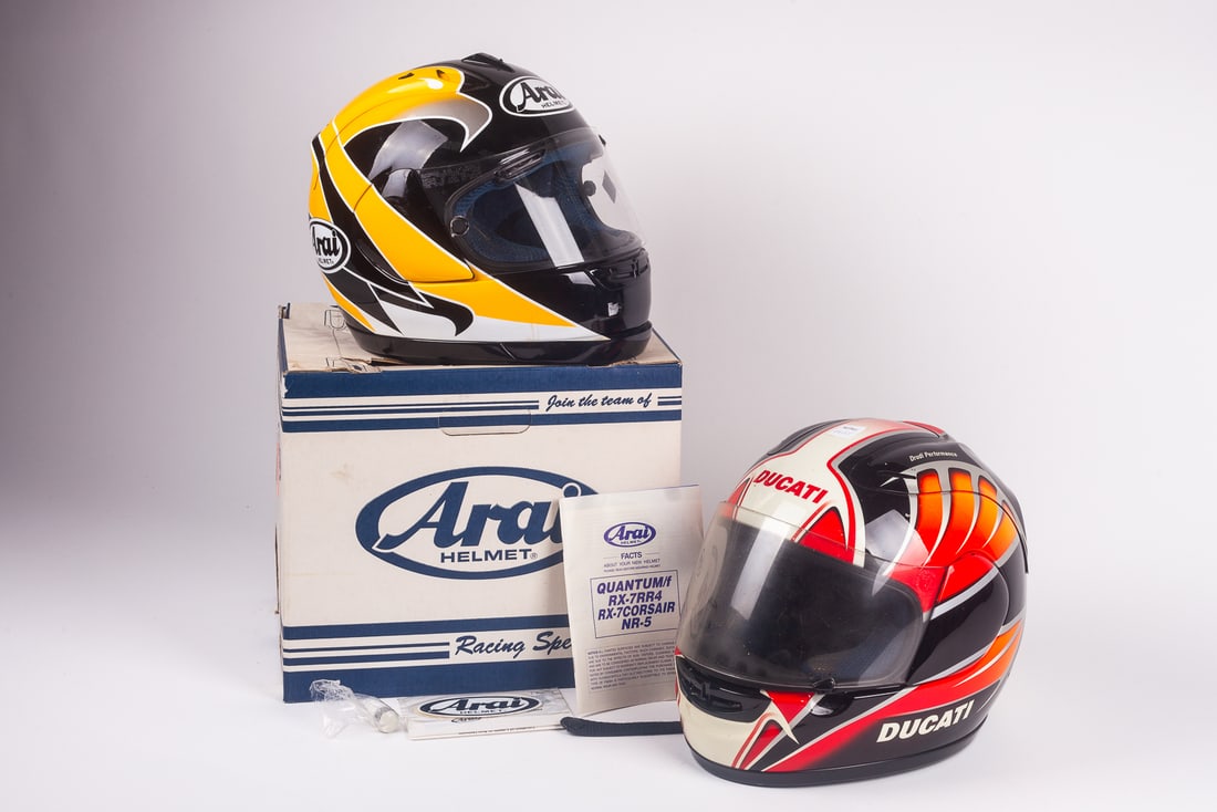 Lot of 2 Racing Helmets - Arai & Ducati by Suomy.: The lot contains 2 racing helmets. First, there is an Arai model RX-7RR4 Snell Dot helmet, in black, yellow, and white. It is a size S or 6 3/4" - 6 7/8". The chin lining has become unglued. Next, the