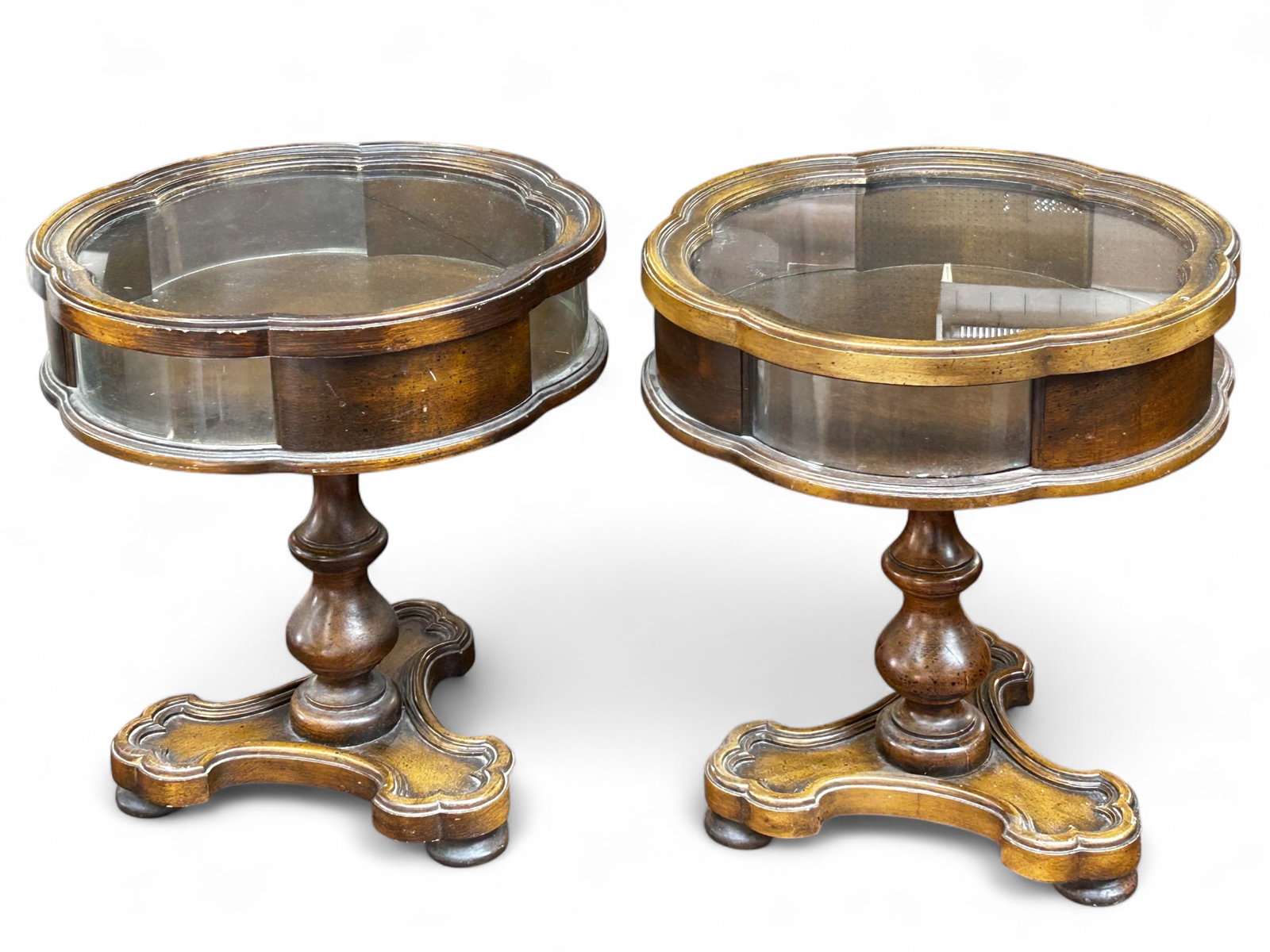 Pair of Pedestal Vitrine Tables.: These walnut tone wood vitrines have glass tops and curved glass side display panels. They stand on pedestal legs and bun feet. The tops are removable. While they could use a little cleaning, both tab
