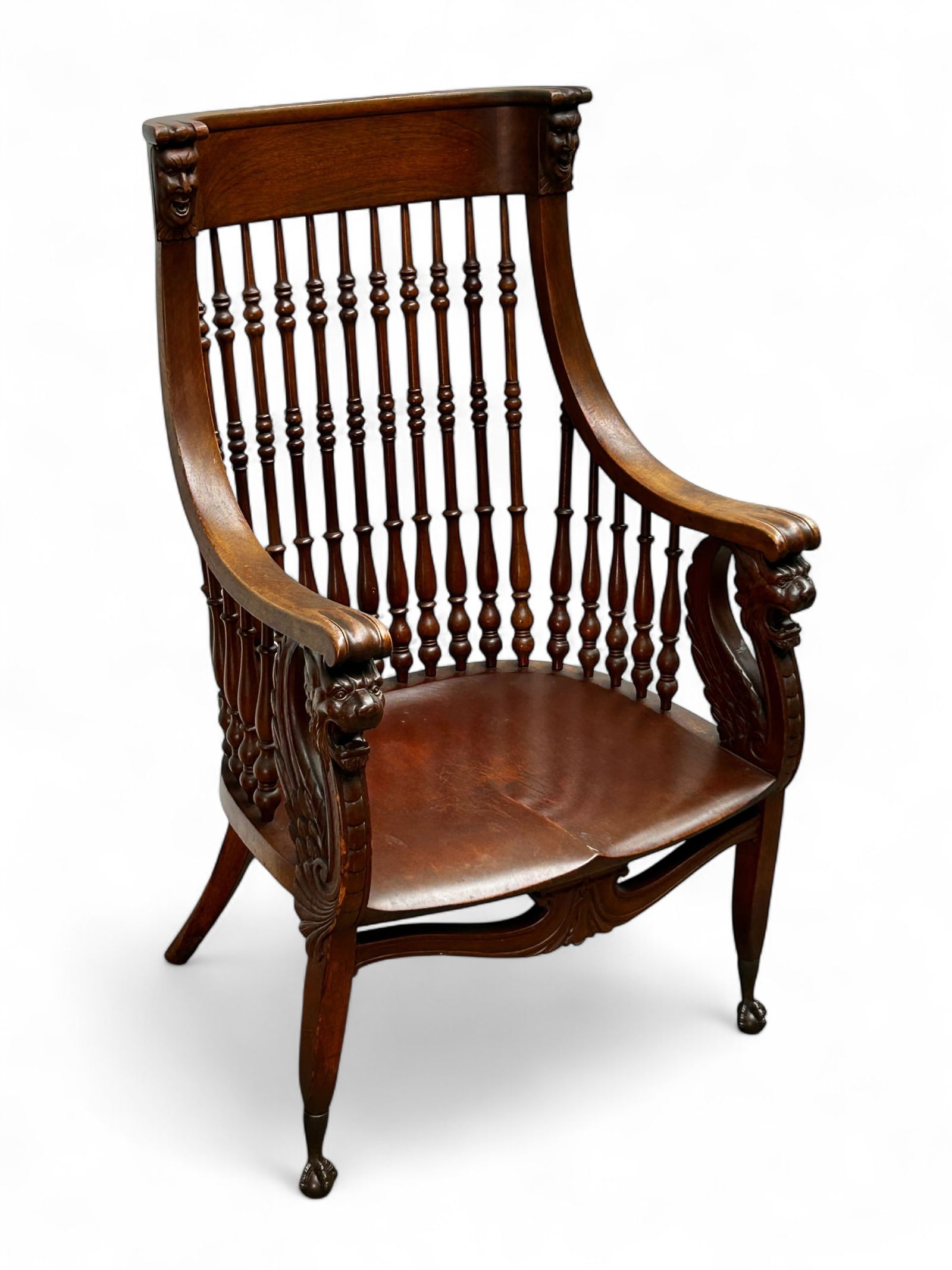 Antique Carved Walnut Spindle Back Chair.: The chair is decorated with carvings of faces and lion heads. It has a spindle back and ball and claw feet. The piece is in sturdy condition, with a few scratches. It measures 24 1/2" wide, 18" deep,