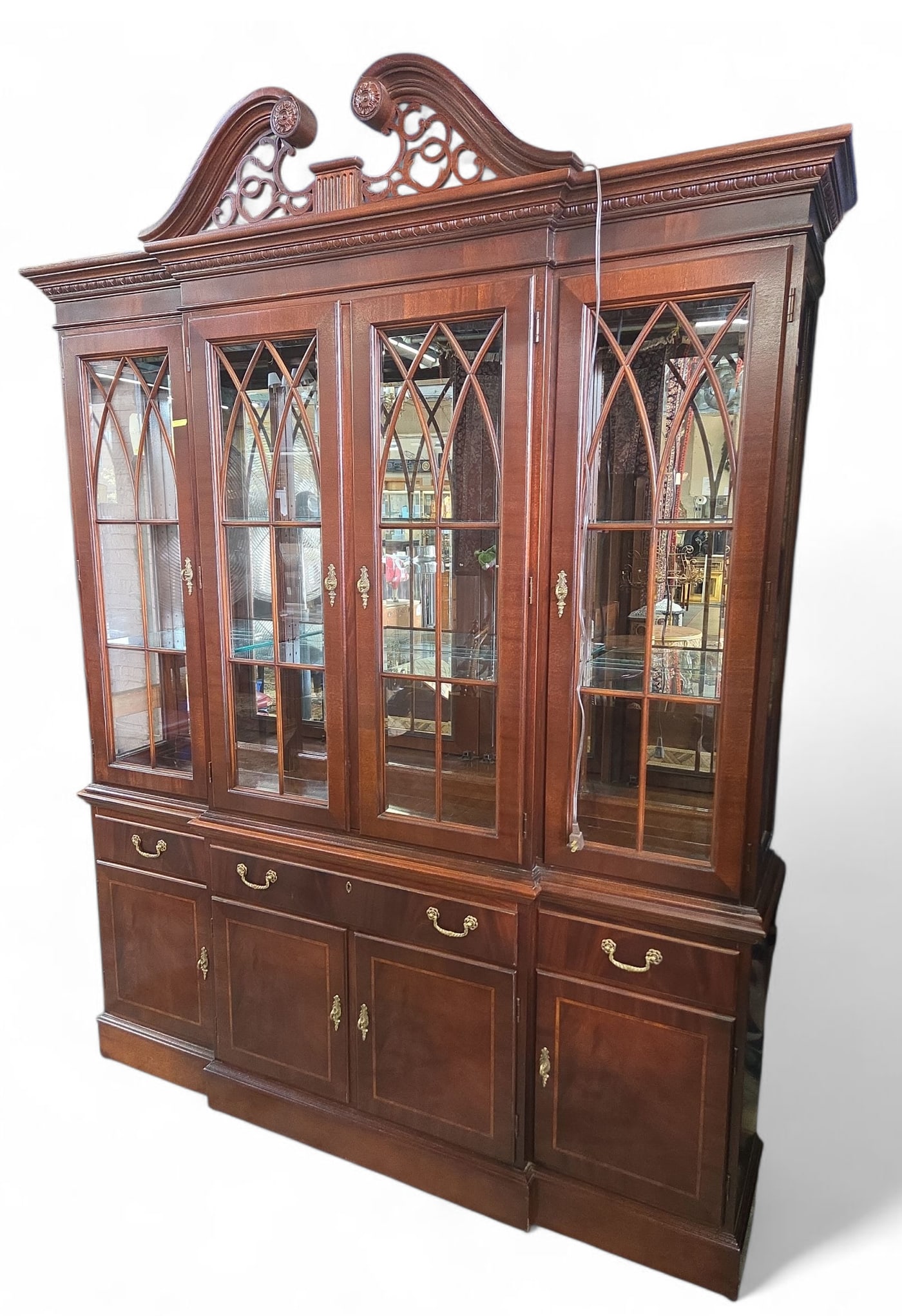 Ethan Allen Mahogany China Cabinet.: This signed banded mahogany display or china cabinet has a carved crest, four glass doors, fretwork designs, interior lights, a mirrored back, and six adjustable glass shelves. The lower section has t