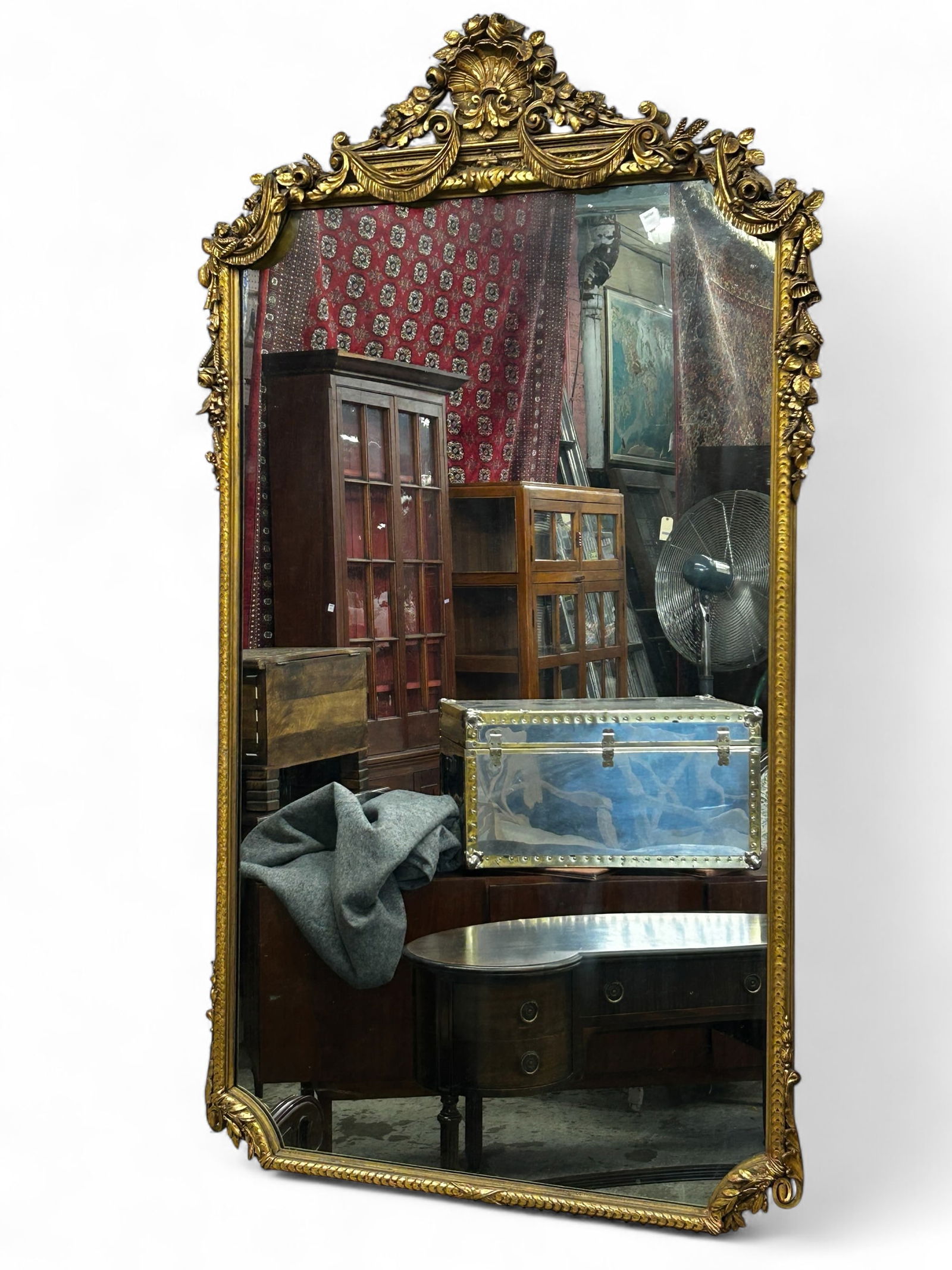 Large Gilt Rococo Style Wall Mirror.: The frame is decorated with carvings of drapery, roses, and acanthus leaves. The frames culminates with a pierced shell carving on top of the piece. There are a few scratches and marks, but overall, t