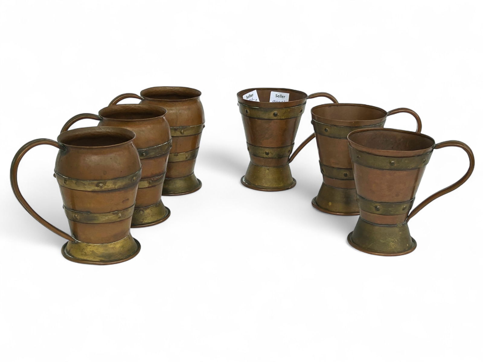 Arts & Crafts Copper & Brass Cups, Hector Aguilar.: The lot contains 6 copper and brass hand wrought cups in two distinct shapes. All of the cups are branded Taxco, along with the Hector Aguilar logo on the undersides. The largest cups measure 5 1/2" x