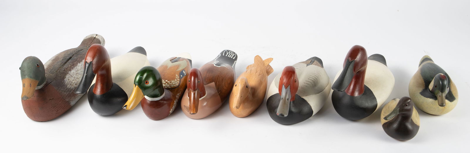 Lot of 9 Carved Wood Duck Decoys, inc. Anderlik.: The duck with the red head and gray bill is signed, "Redhead by my hand J. Anderlik". One of the larger ducks with a red head is signed, "Capt. Harry Jobes". One of the smaller ducks is signed, "Bud K