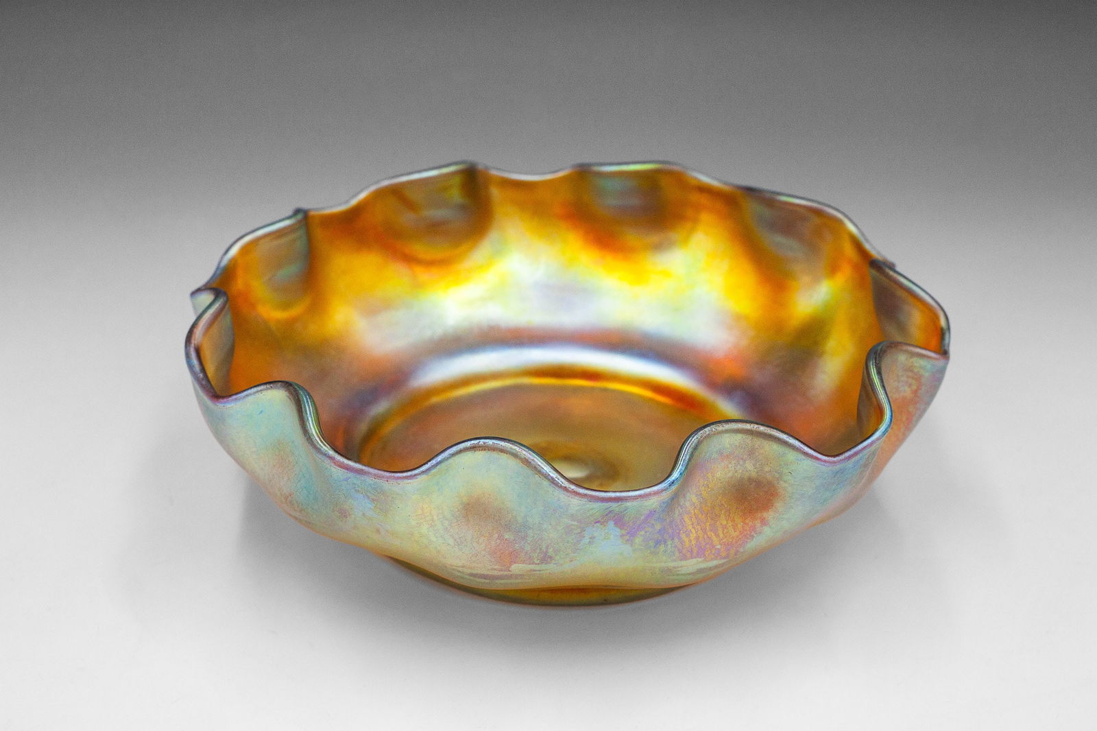 L.C.T. Tiffany Favrile Glass Ruffled Finger Bowl.: This iridescent glass bowl looks to be in very good condition. It measures 6 3/4" across and 2" tall. In-house shipping is available. Please see our website regarding in-house shipping procedures.
