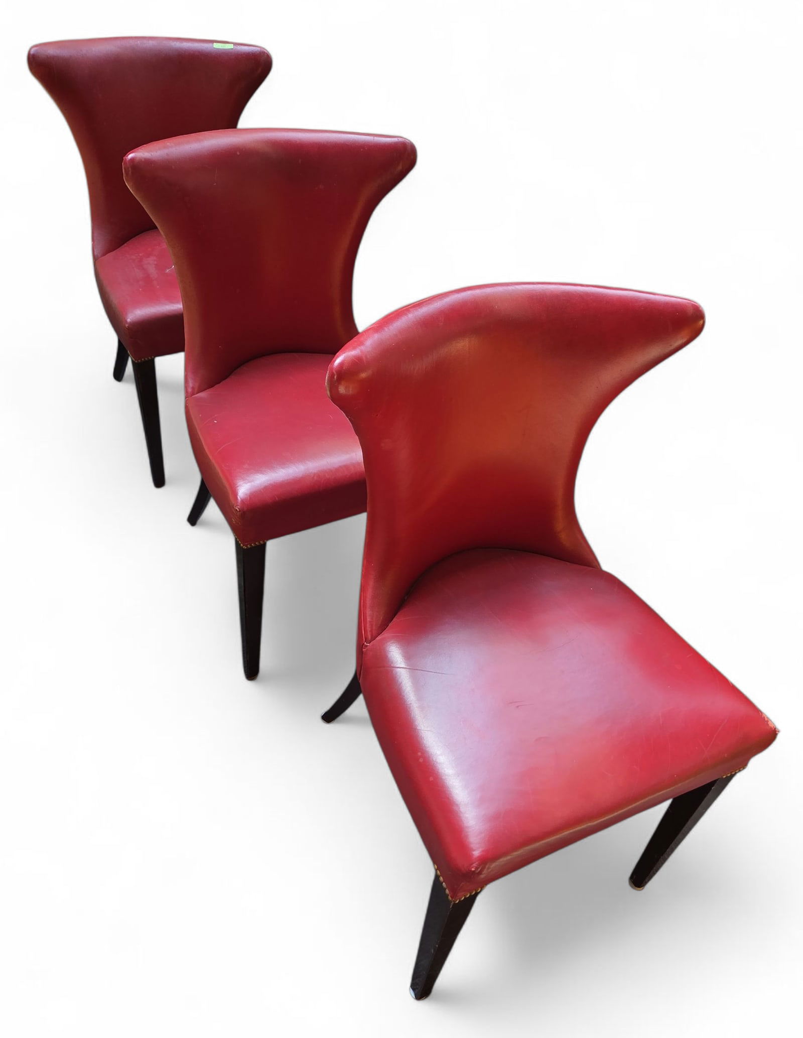3 Retro Holly Hunt Red Leather Dining Chairs.: The vintage chairs have tapered legs, brass nail head trim around the legs, and are upholstered in red lipstick leather. Each piece measures 34 1/2" x 21 3/4" x 21 1/4". One of the seats has a tear, a