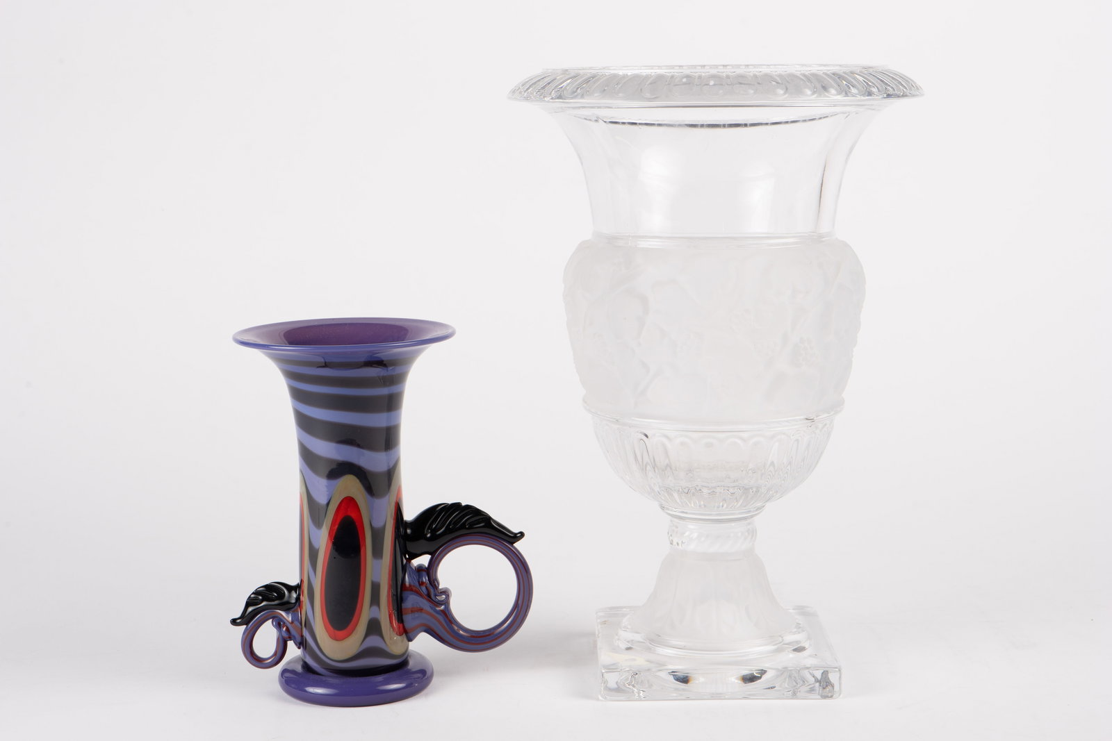 R. Levin Art Glass Vase & Versailles Crystal Vase.: The lot contains 2 items. First, there is a purple trumpet art glass vase by Robert Levin, signed on the underside along with the date, 1985. It measures 7" x 6" x 4 1/4". Next, there is a large cryst