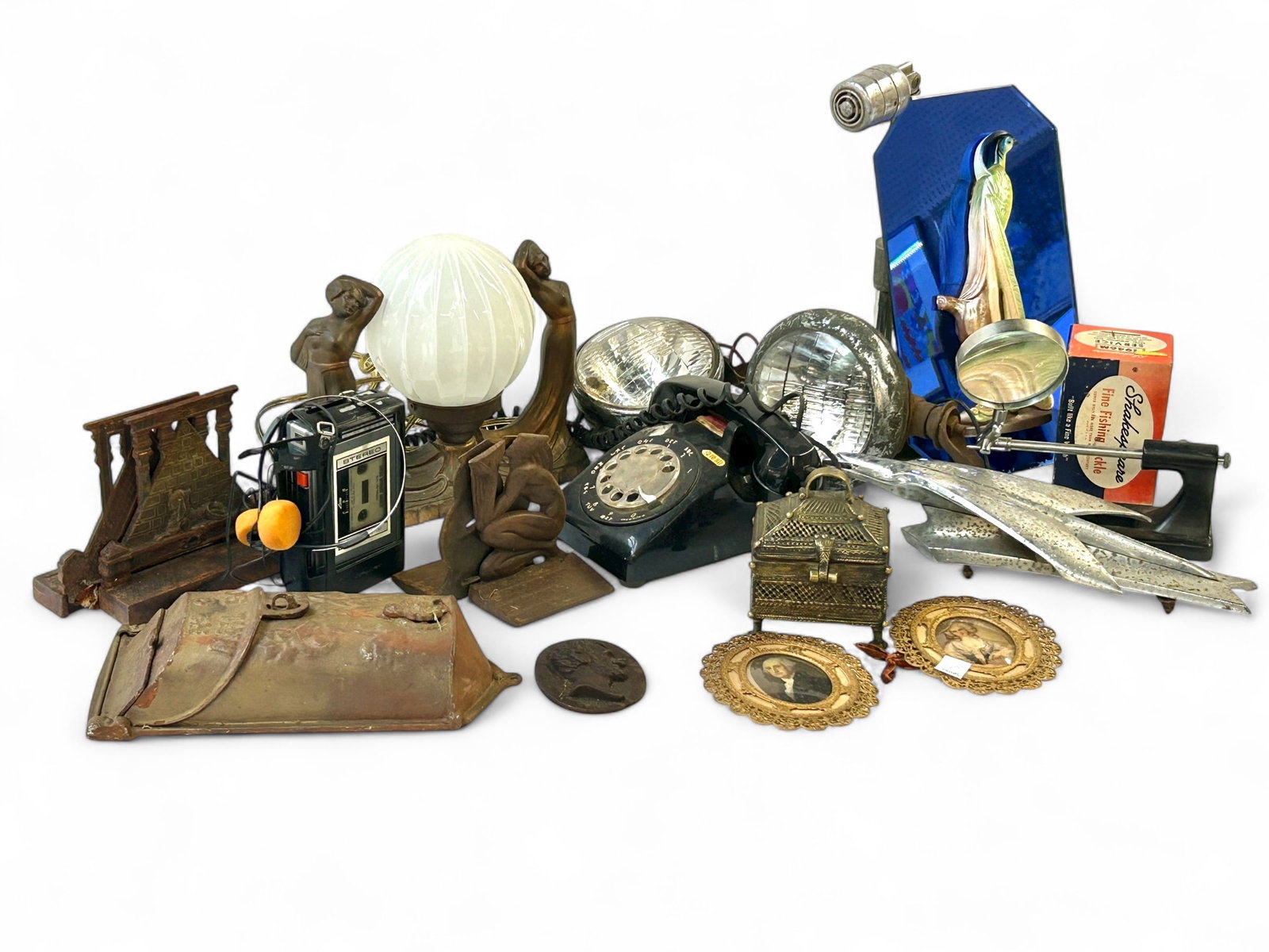 Lot: Art Deco Decor, Fog Lamps, etc.: This lot includes Egyptian Revival Art Deco bookends, an Art Deco globe lamp w/ partially nude ladies, an eagle hood ornament (some rust), a Shakespeare Wondereel, a lot of two vintage fog lamps, a vi