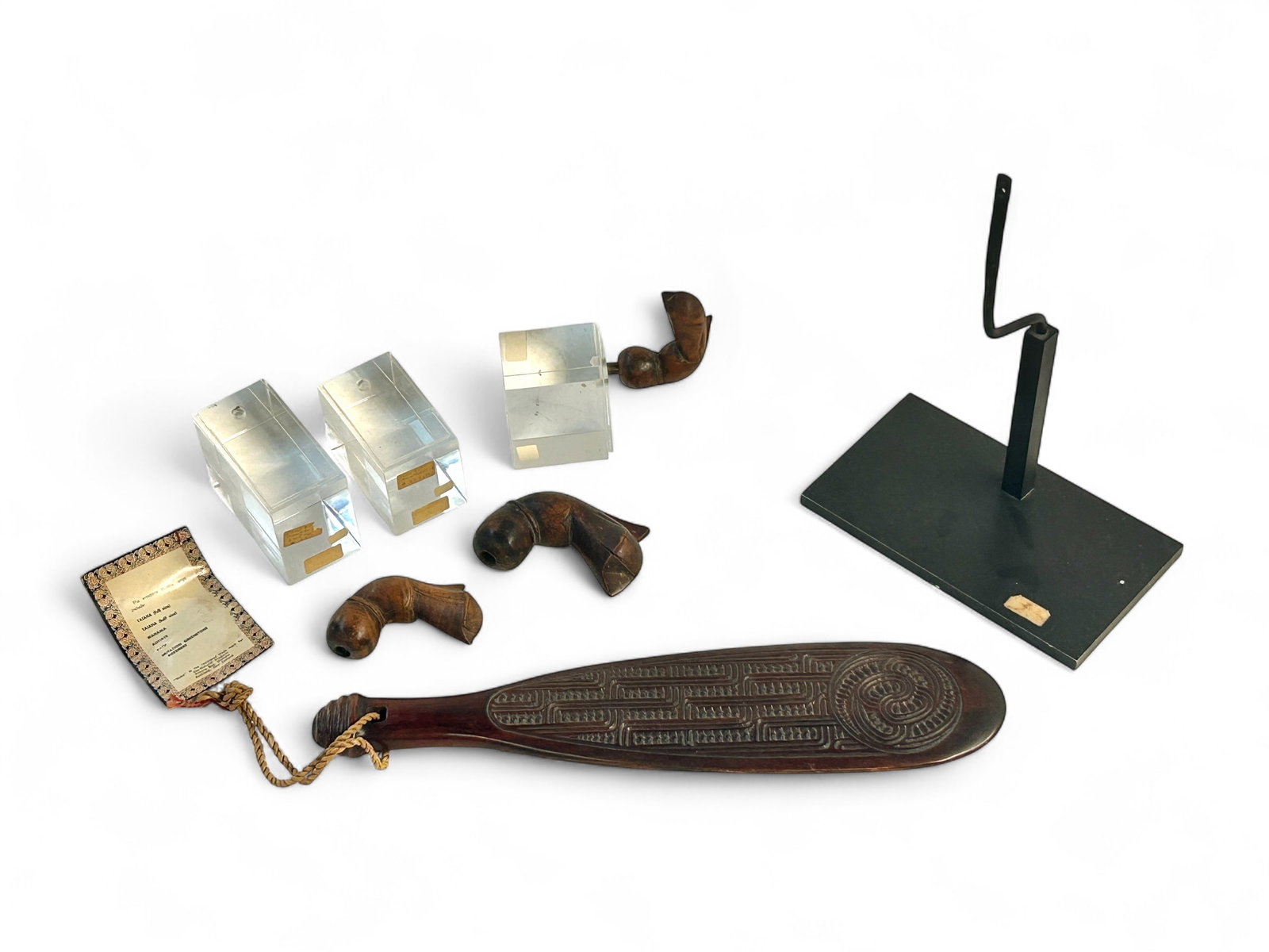 Lot: Maori Carved Patu & 3 Buginese Kris Handles.: The lot contains 4 carved wood items on stands. First, there is a carved Matai hardwood Maori Moko Patu from New Zealand on a black metal stand. The Patu measures 15 1/4" x 4". Next, there are 3 Bugin