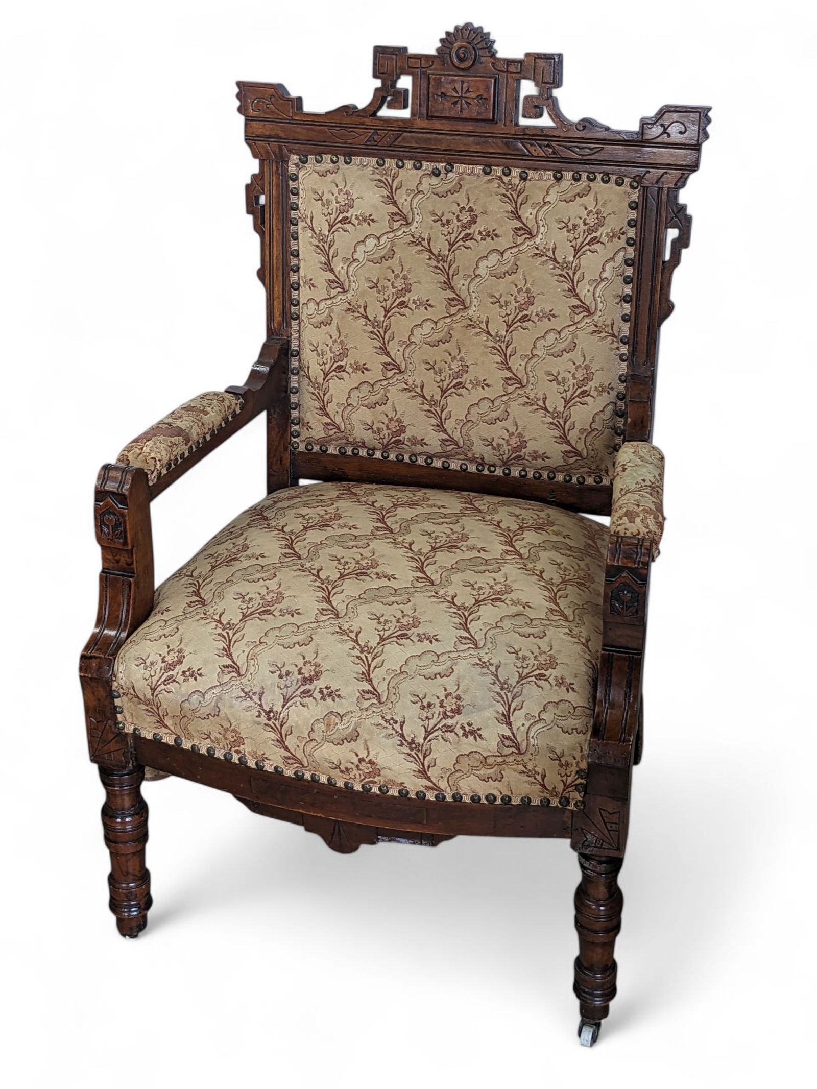 Eastlake Victorian Parlor Chair.: This elegant walnut armchair has a beautifully carved frame with floral upholstery and nailhead trim. The front legs have porcelain casters. The fabric shows wear (especially on the arms), and some of