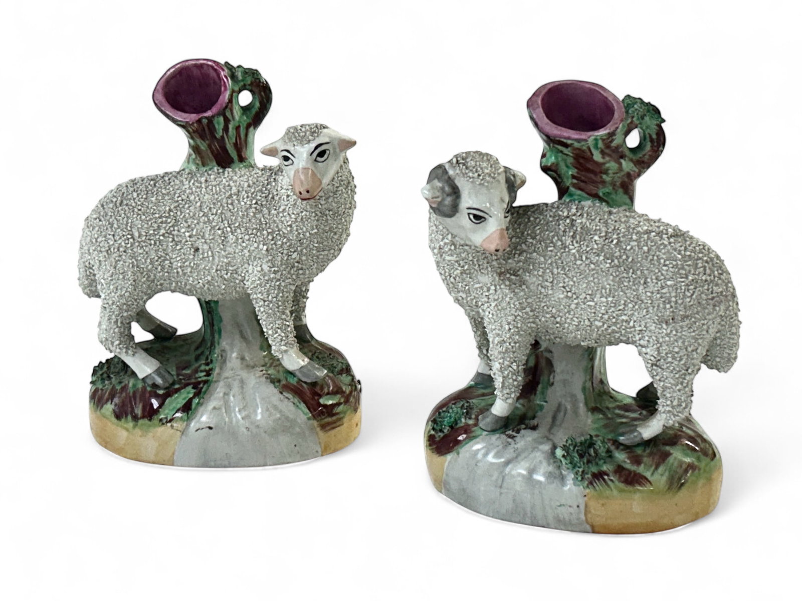 Pair of Staffordshire Sheep Spill Vases.: The lot contains a pair of Staffordshire Ware England vases. They feature textured sheep with different head positions, and a background painted in green, brown and pink. Each piece measures 7 3/8" x 