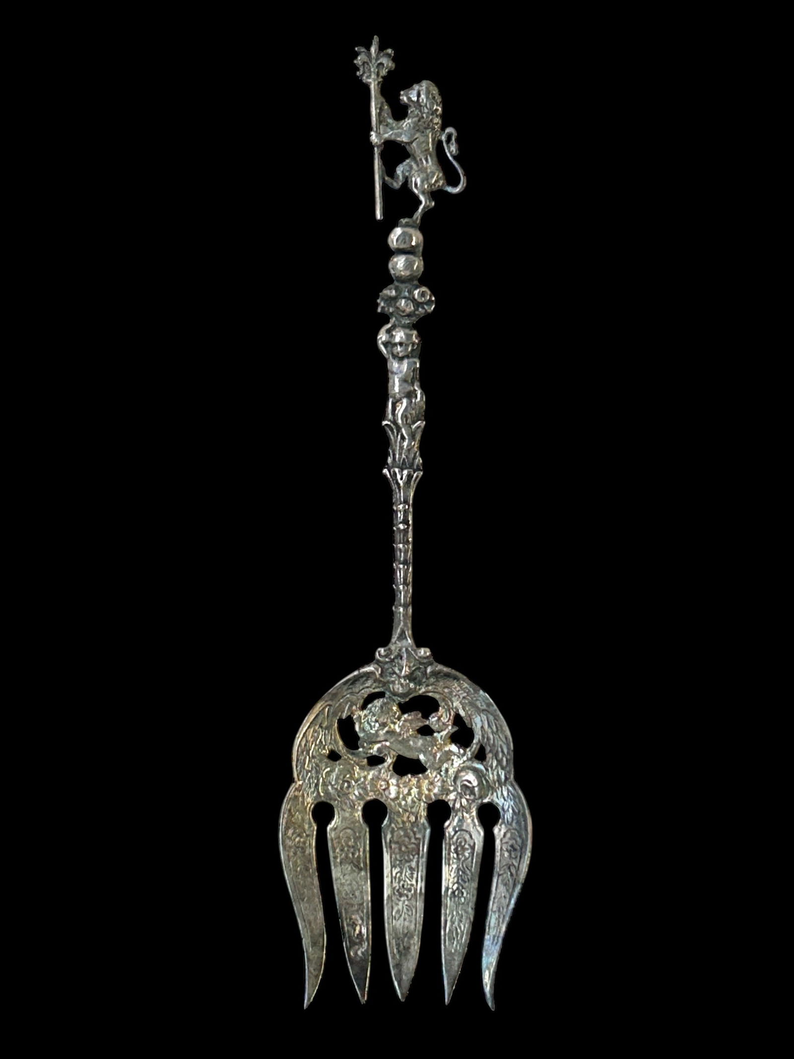 Antique Ornate Sterling Silver Serving Fork.: This possibly French antique serving fork features the figure of a lion at the top, and a cherub on a pierced background near the 5 prongs, which are decorated with flowers. The piece also has a face
