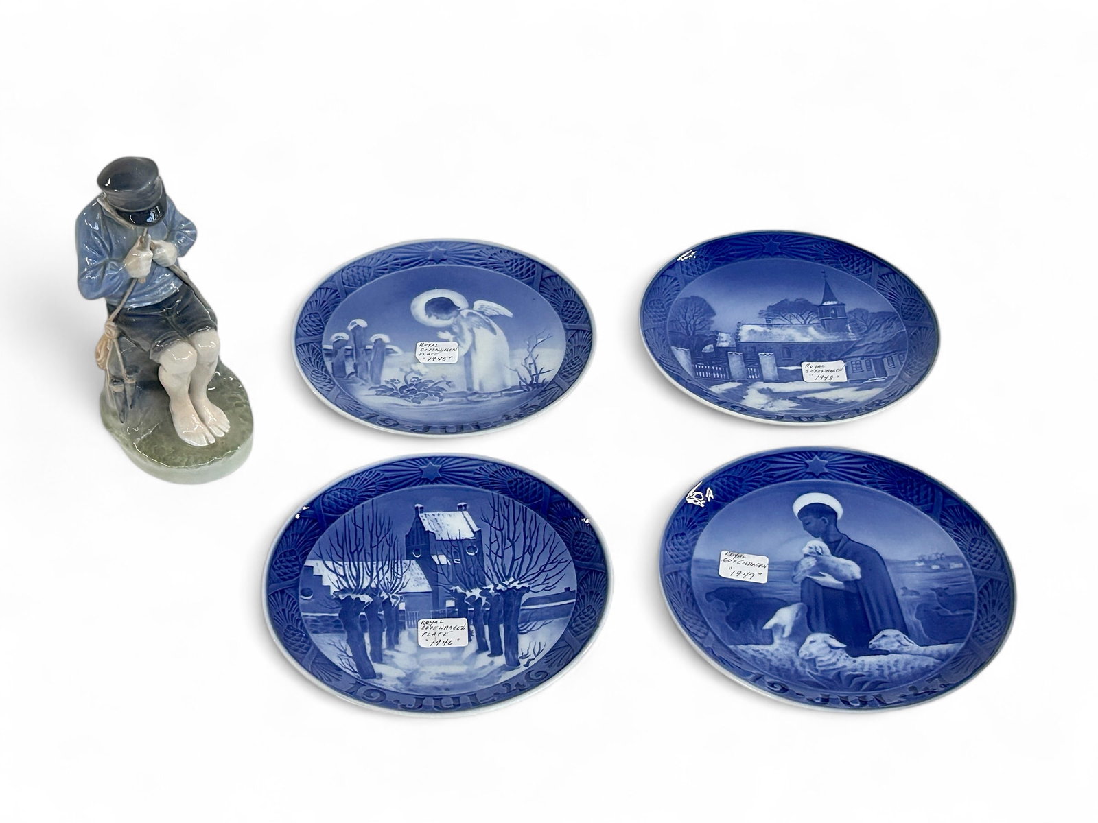 Royal Copenhagen Figurine, 1945-1948 Plates.: This lot includes four Royal Copenhagen 7 3/8" plates (years 1945, 1946, 1947, and 1948), and a Royal Copenhagen 7 1/2" figurine of a boy whittling. All items look to be in good condition. In-house sh