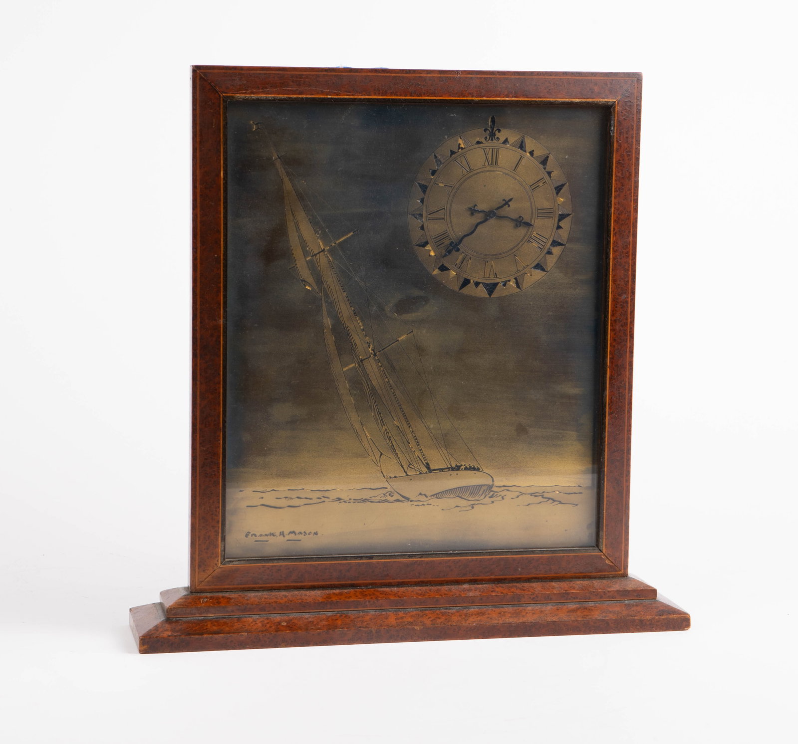 Slim Wood Clock w/ Sailboat - Frank H. Mason.: The maritime timepiece displays as a flat picture frame with a tiered stand. The front of the piece features an etched and enameled brass plaque with the clock face and the image of a slanted sailboat