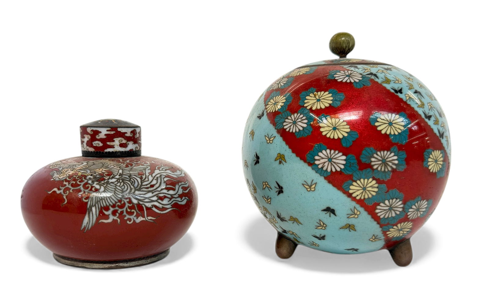 2 Japanese Meiji Period Cloisonne Enamel Jars.: The squat jar has a silver colored metal bottom and a silver color metal interior. It has phoenix designs on it. The round jar has butterfly and flower designs on it. Both pieces are in good overall c