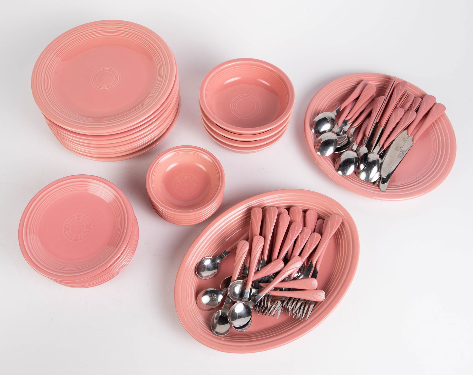 Pink Fiestaware Set - Dishes & Flatware.: The lot includes the following Fiesta Ware pcs.: 10 dinner plates, 9 bread plates (one with a nick on the edge), 4 cereal bowls, 6 fruit bowls, a round platter, an oblong platter, 9 dinner knives, 10